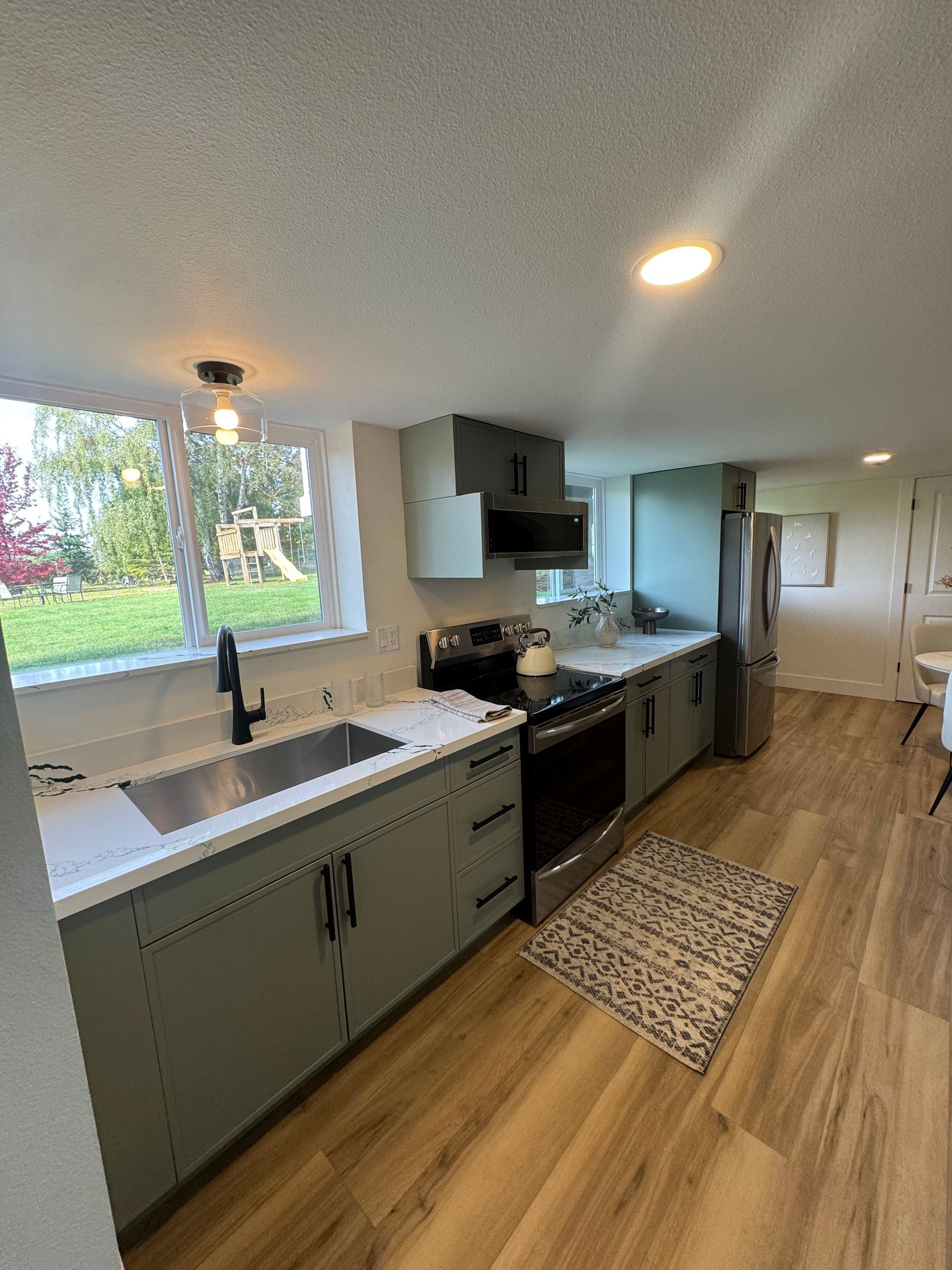 Modern kitchen with wooden cabinets, white countertops, stainless steel appliances, and a skylight.