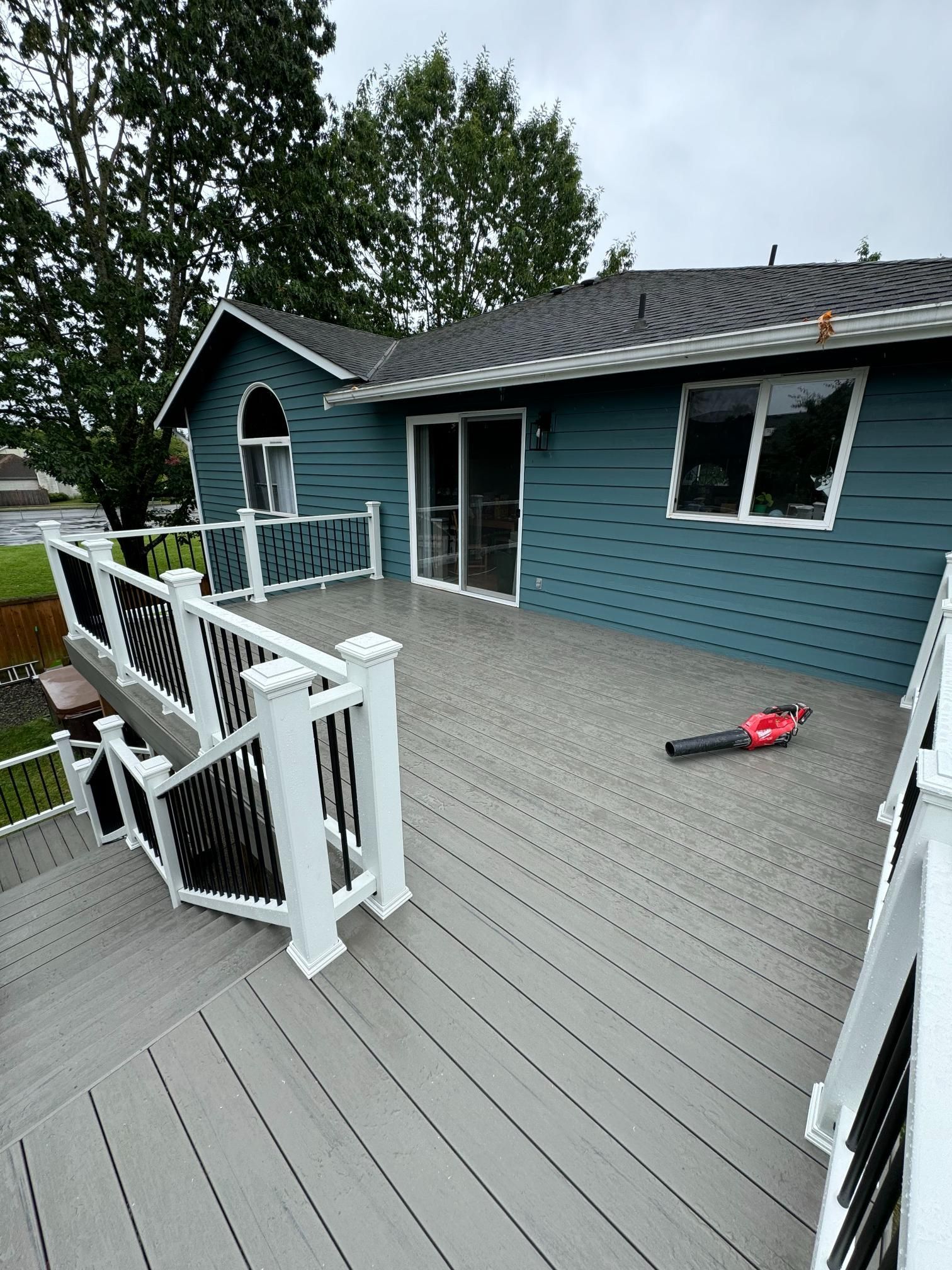 Gray composite deck attached to a blue house with white trim. A leaf blower sits on the deck.