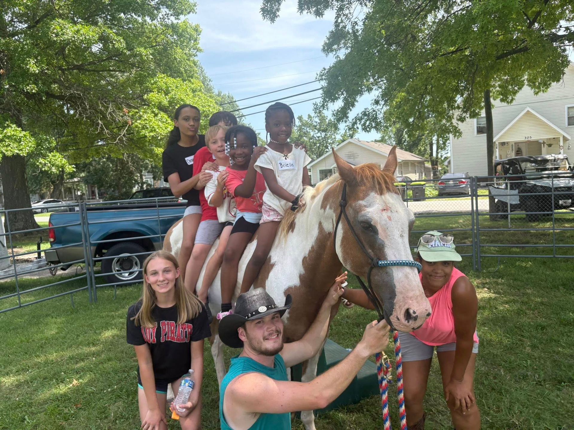 A group of children are riding on the back of a brown and white horse.