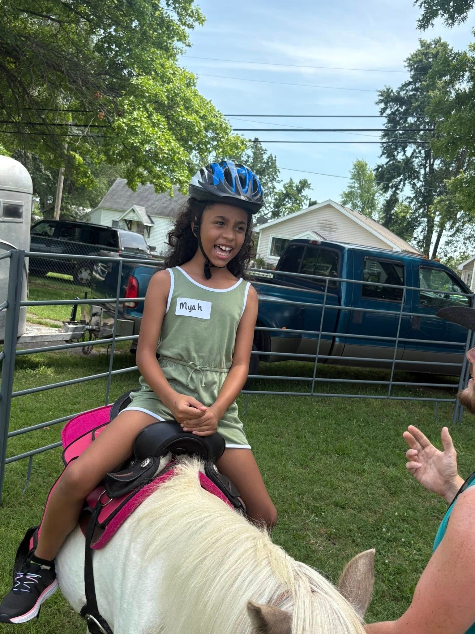 A little girl is riding on the back of a white horse.