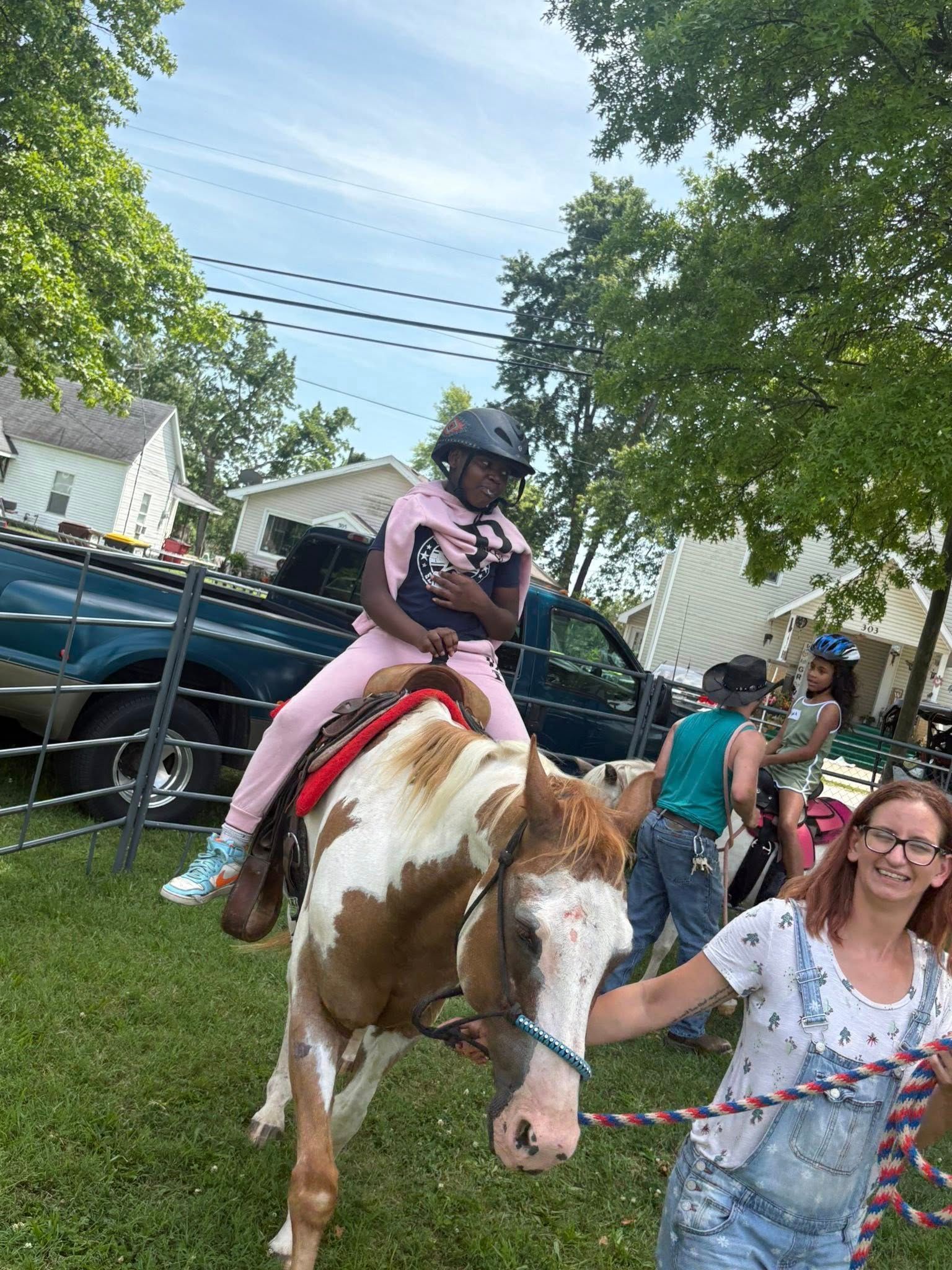 A girl is riding on the back of a brown and white horse.