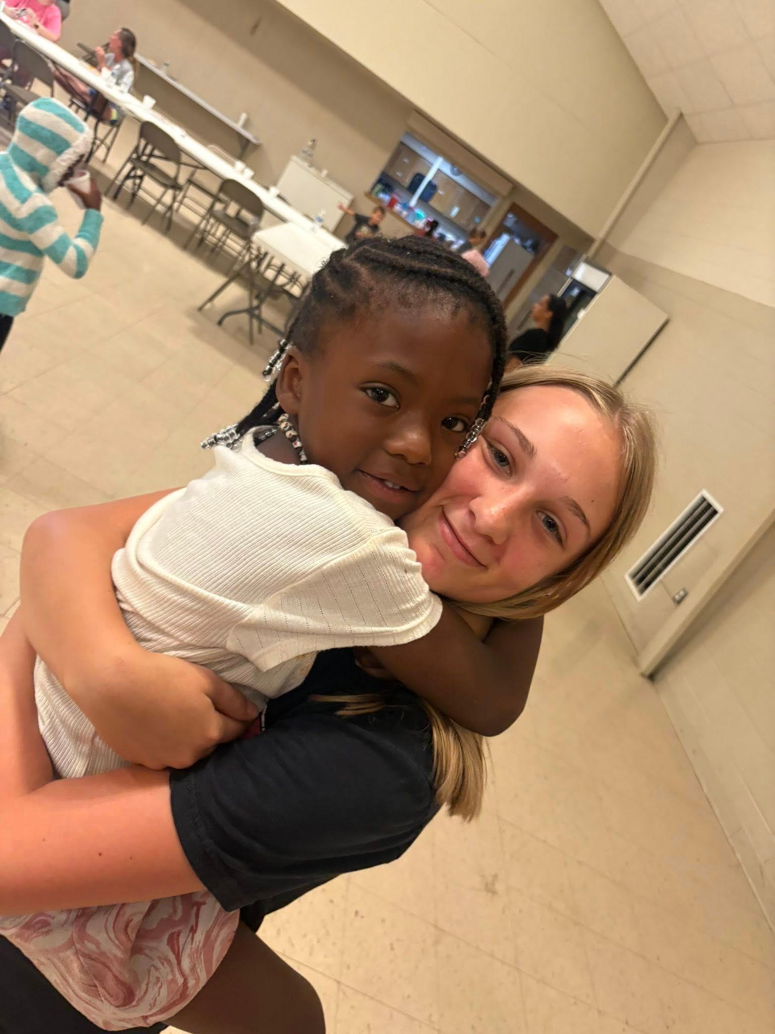 A woman is holding a little girl in her arms in a room.
