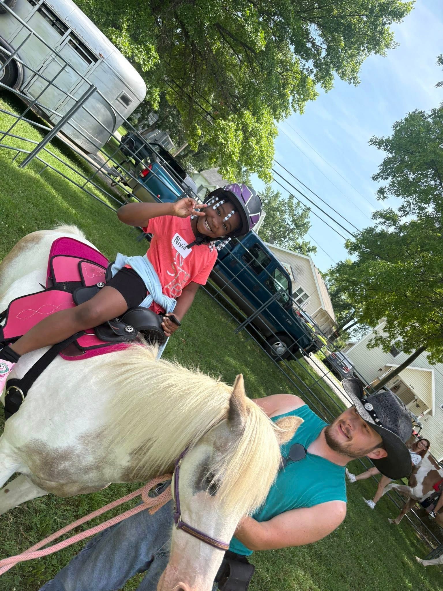 A little girl is riding a pony next to a man in a cowboy hat.