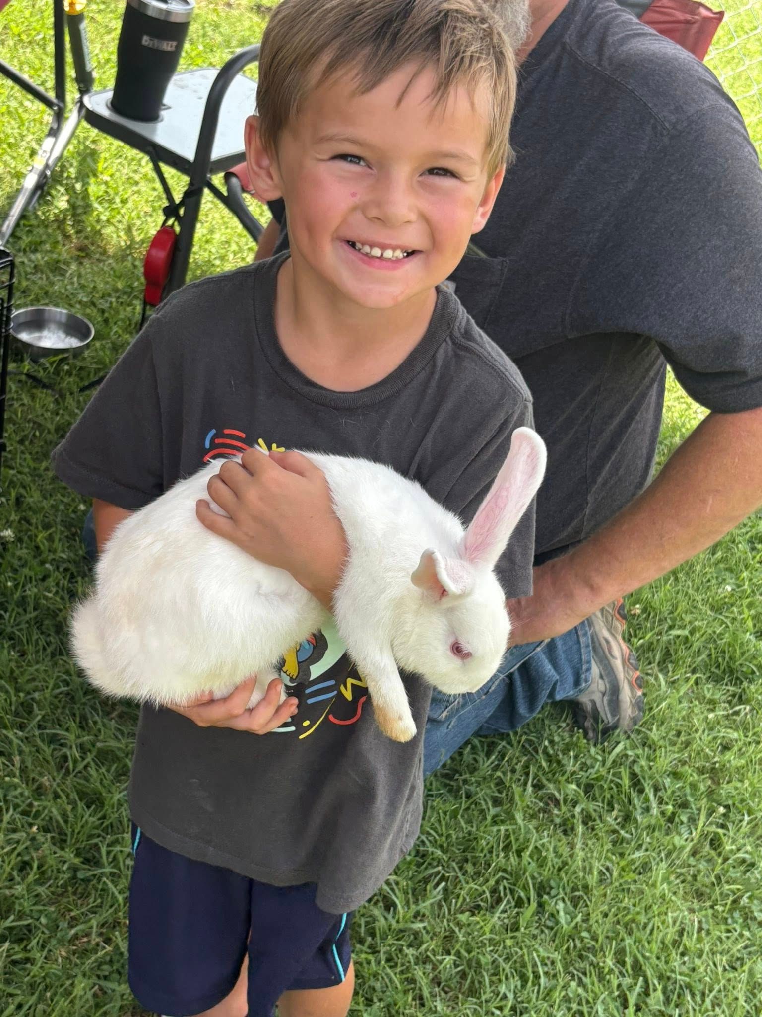 A young boy is holding a white rabbit in his hands.
