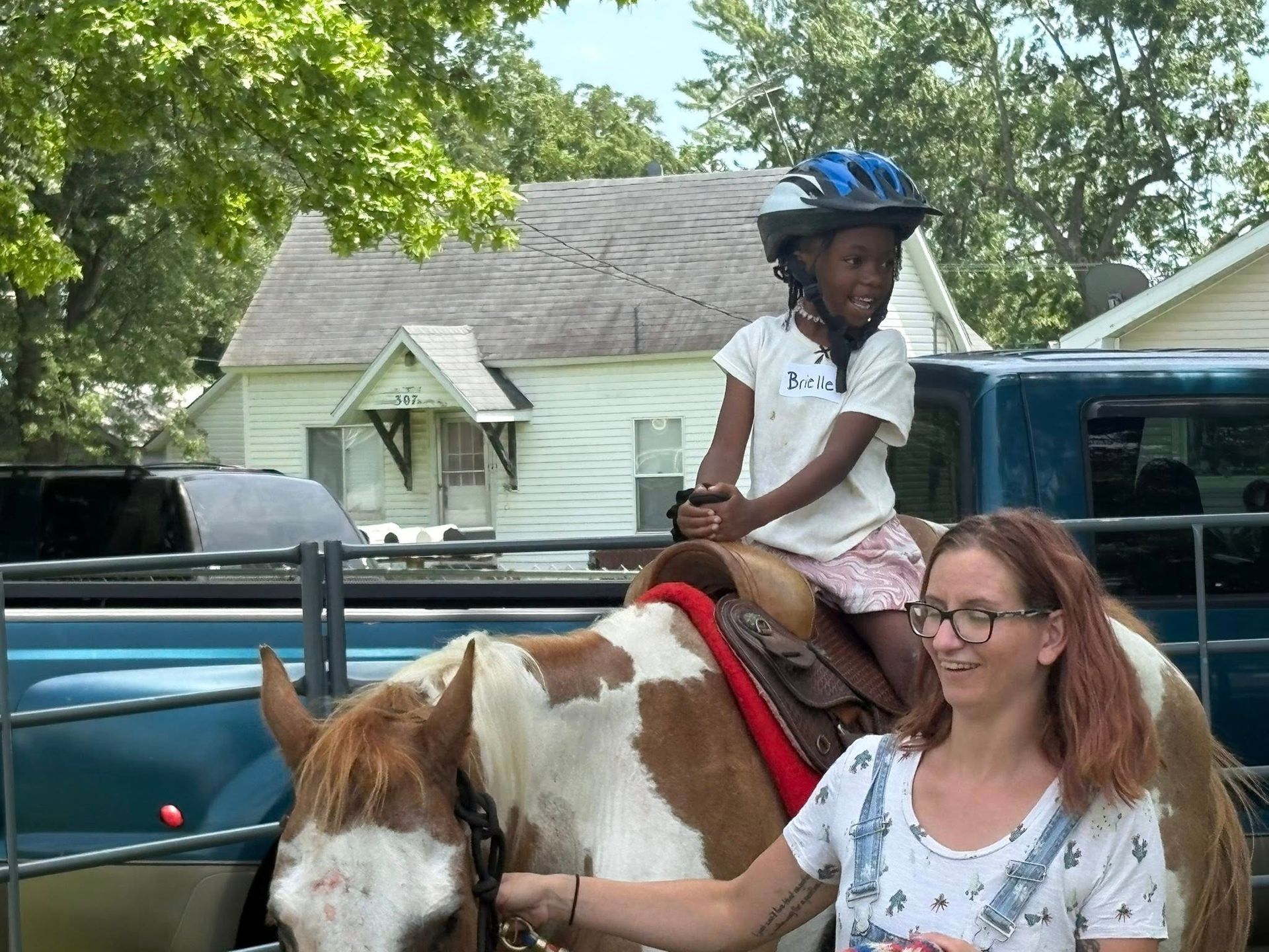 A little girl is riding on the back of a brown and white horse.