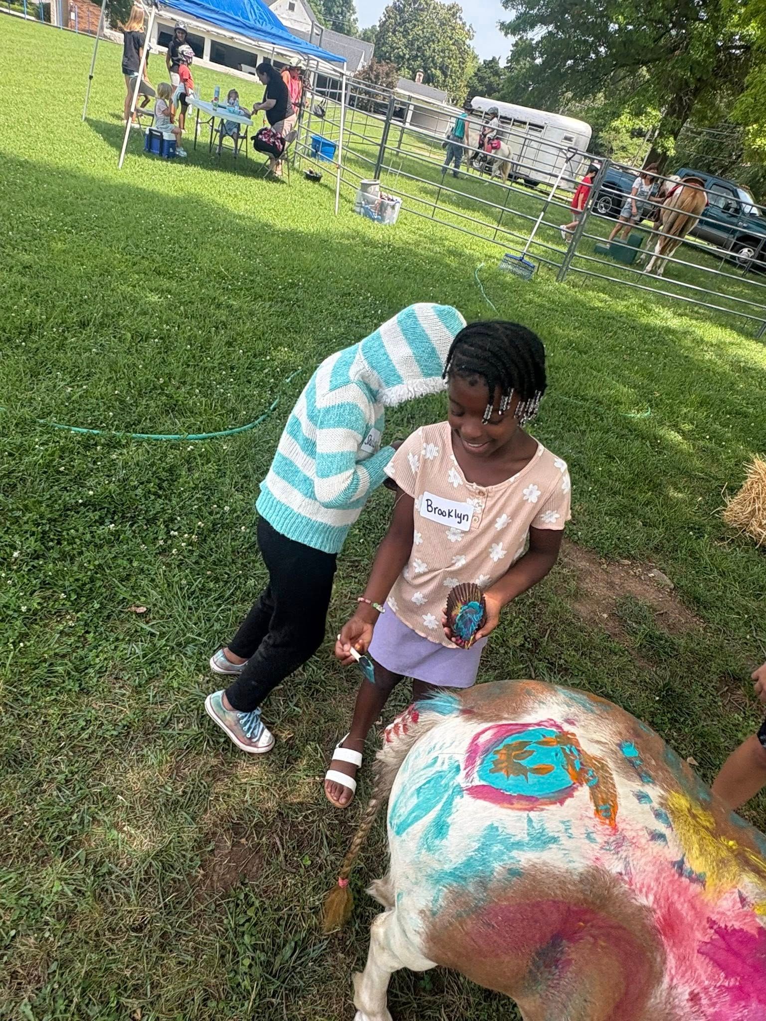 A group of children are painting a sheep in a park.