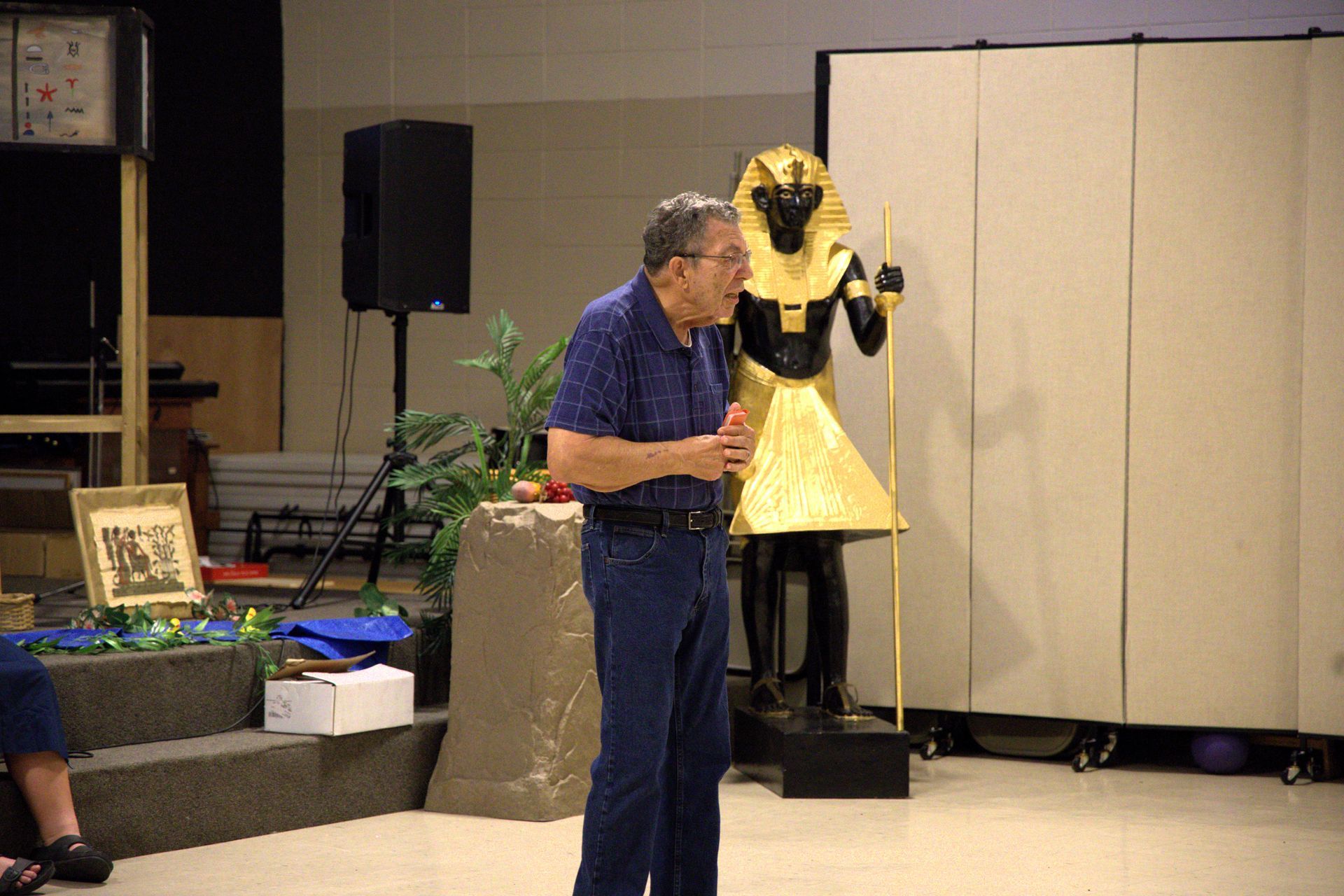 A man in a blue shirt stands in front of a statue