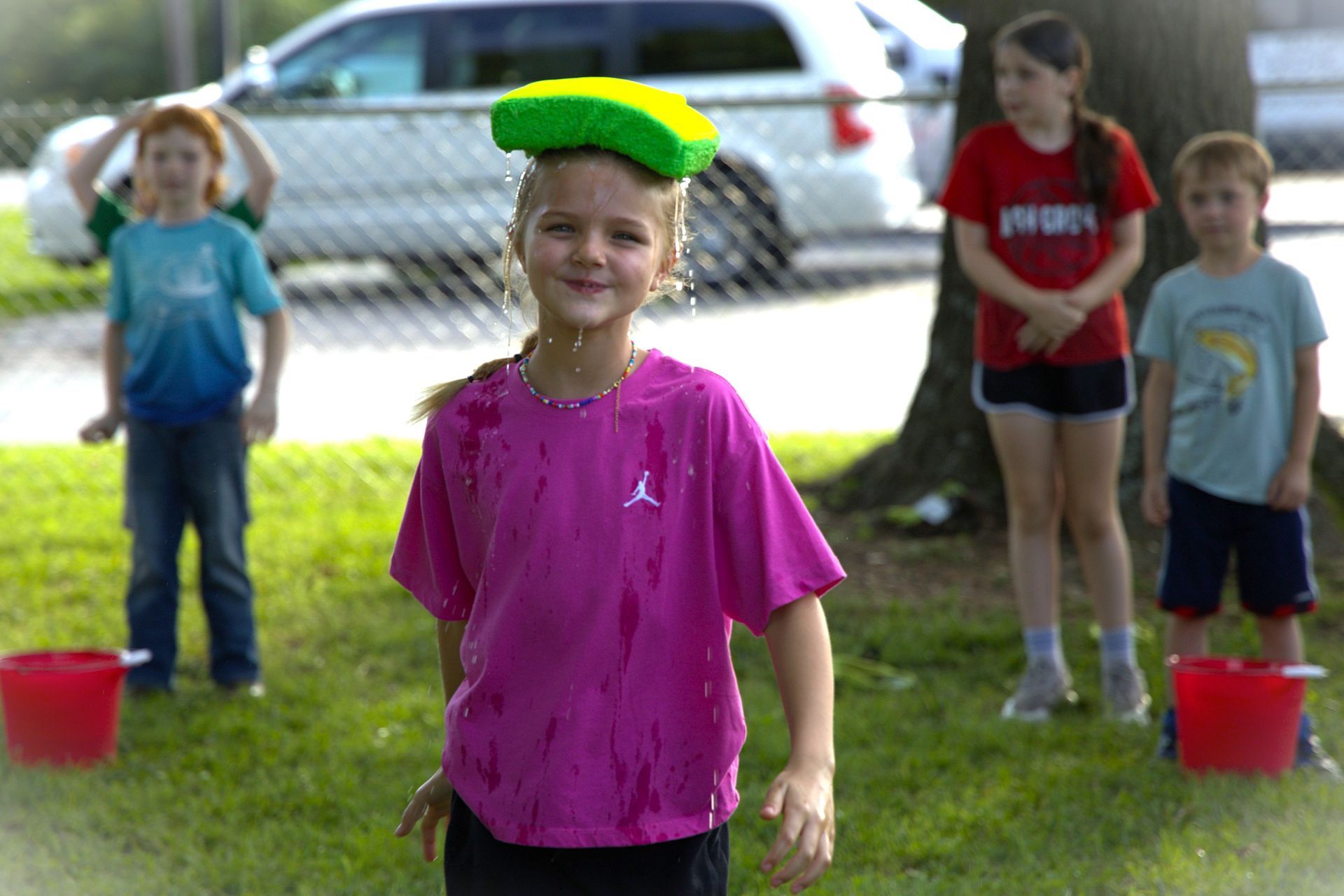 A girl in a pink shirt has a sponge on her head
