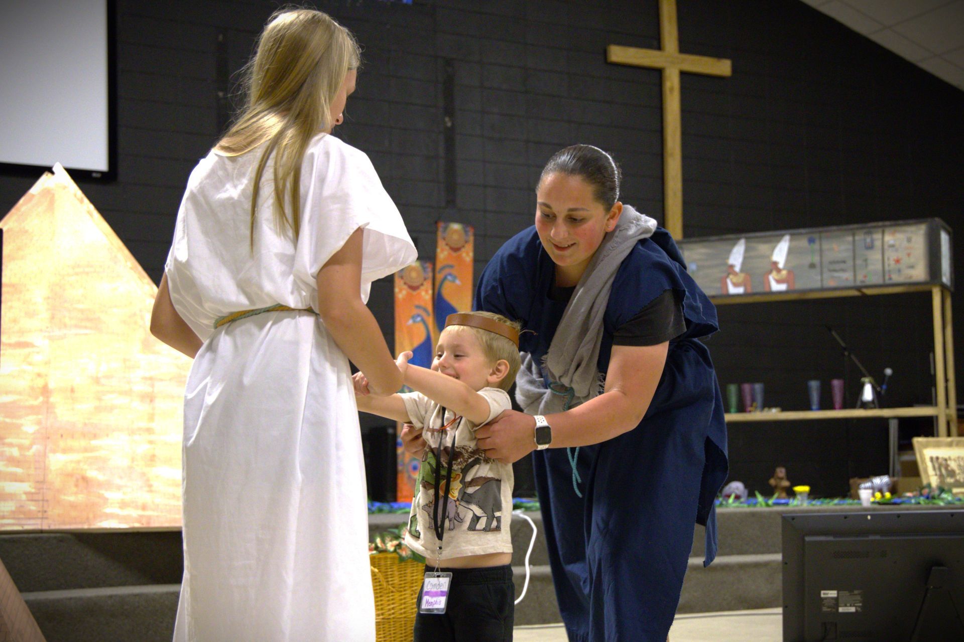 A woman in a white dress is holding a baby in her arms.