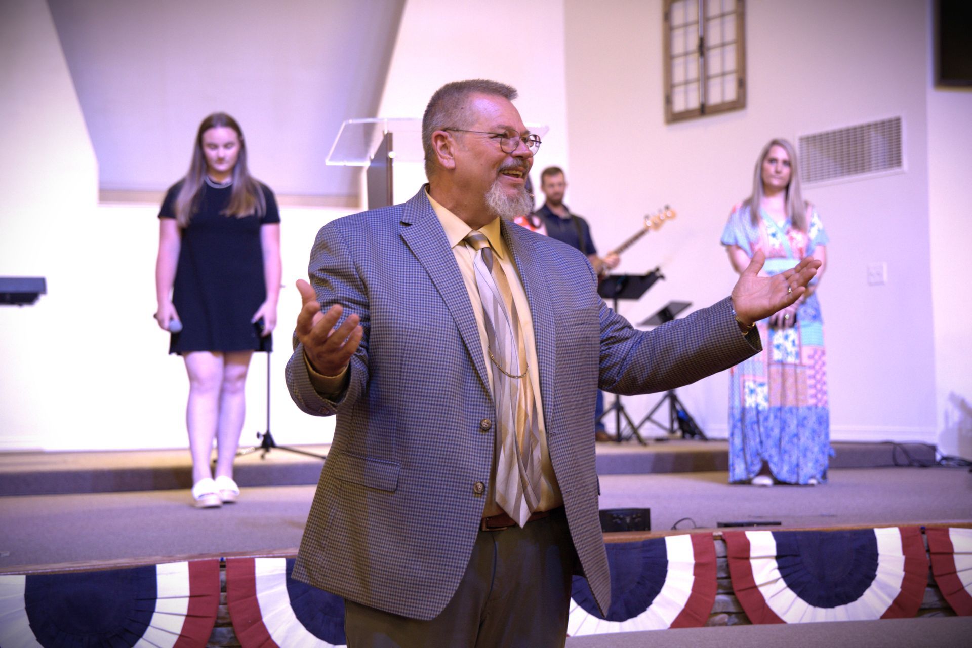 A man in a suit and tie is standing on a stage giving a speech.