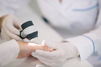 Dermatologo esamina attentamente la mano di una paziente in clinica