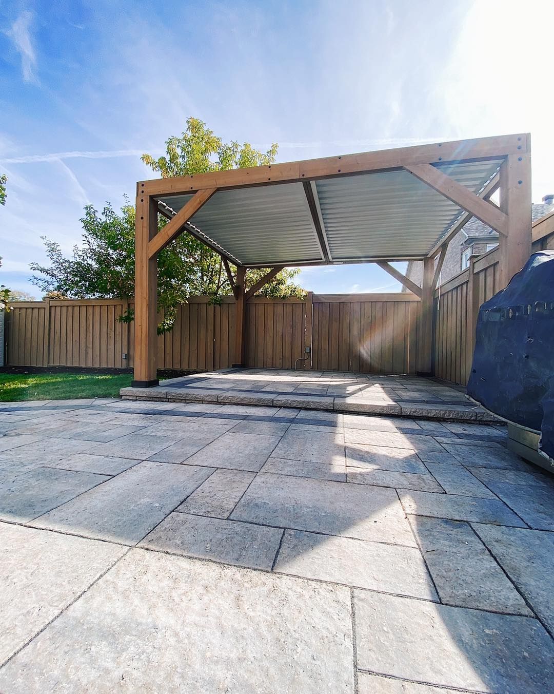 A patio with a wooden pergola and a wooden fence.