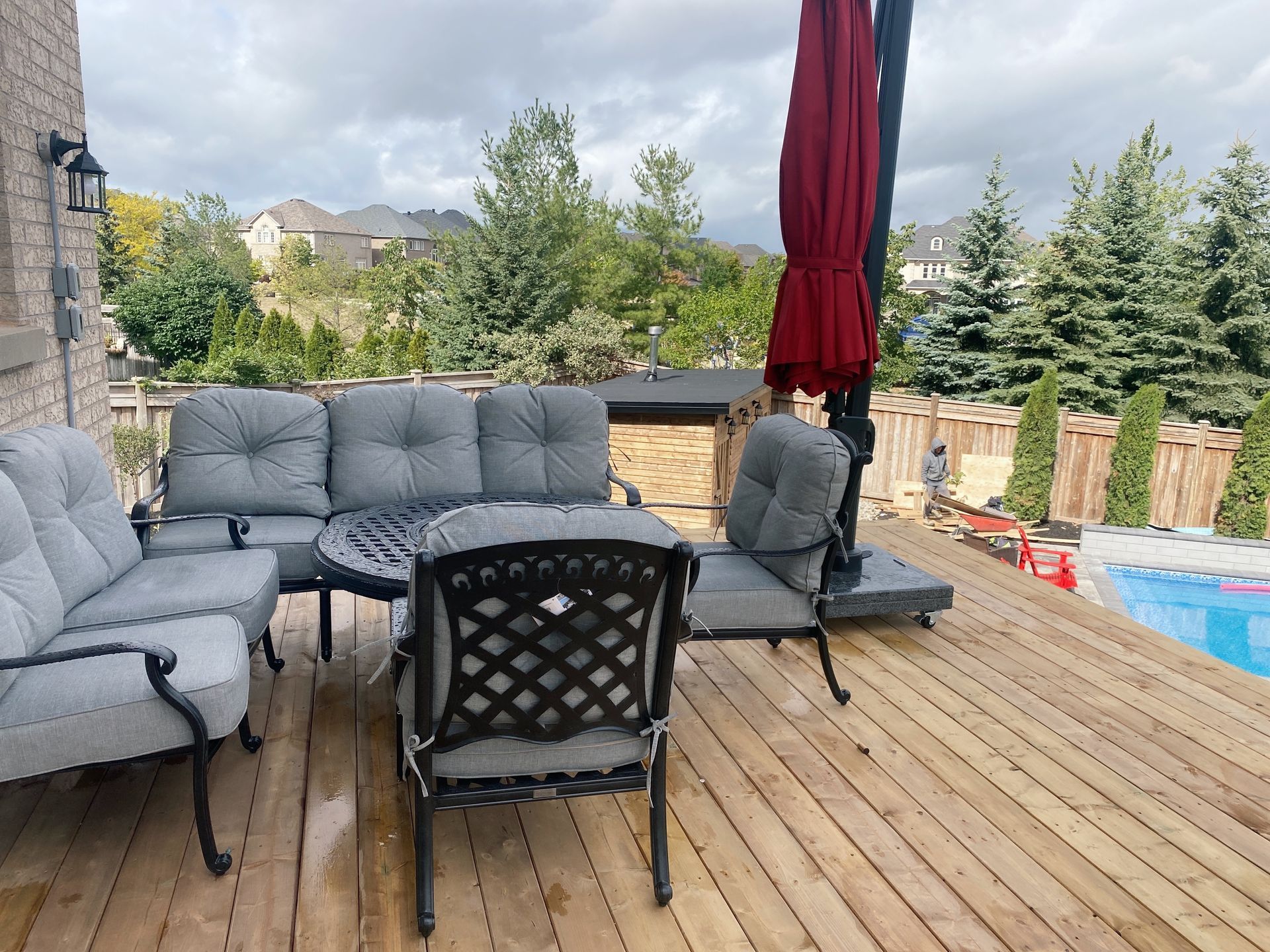 A wooden deck with a couch , chairs , table and umbrella.