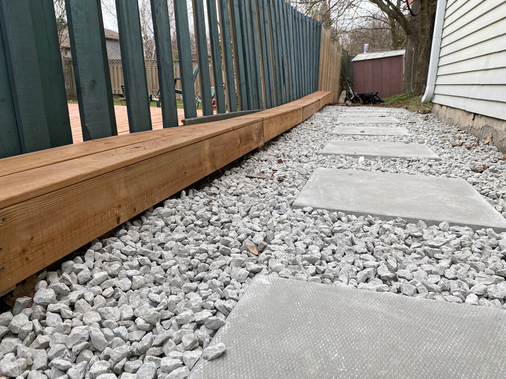 A walkway surrounded by gravel and a wooden fence.