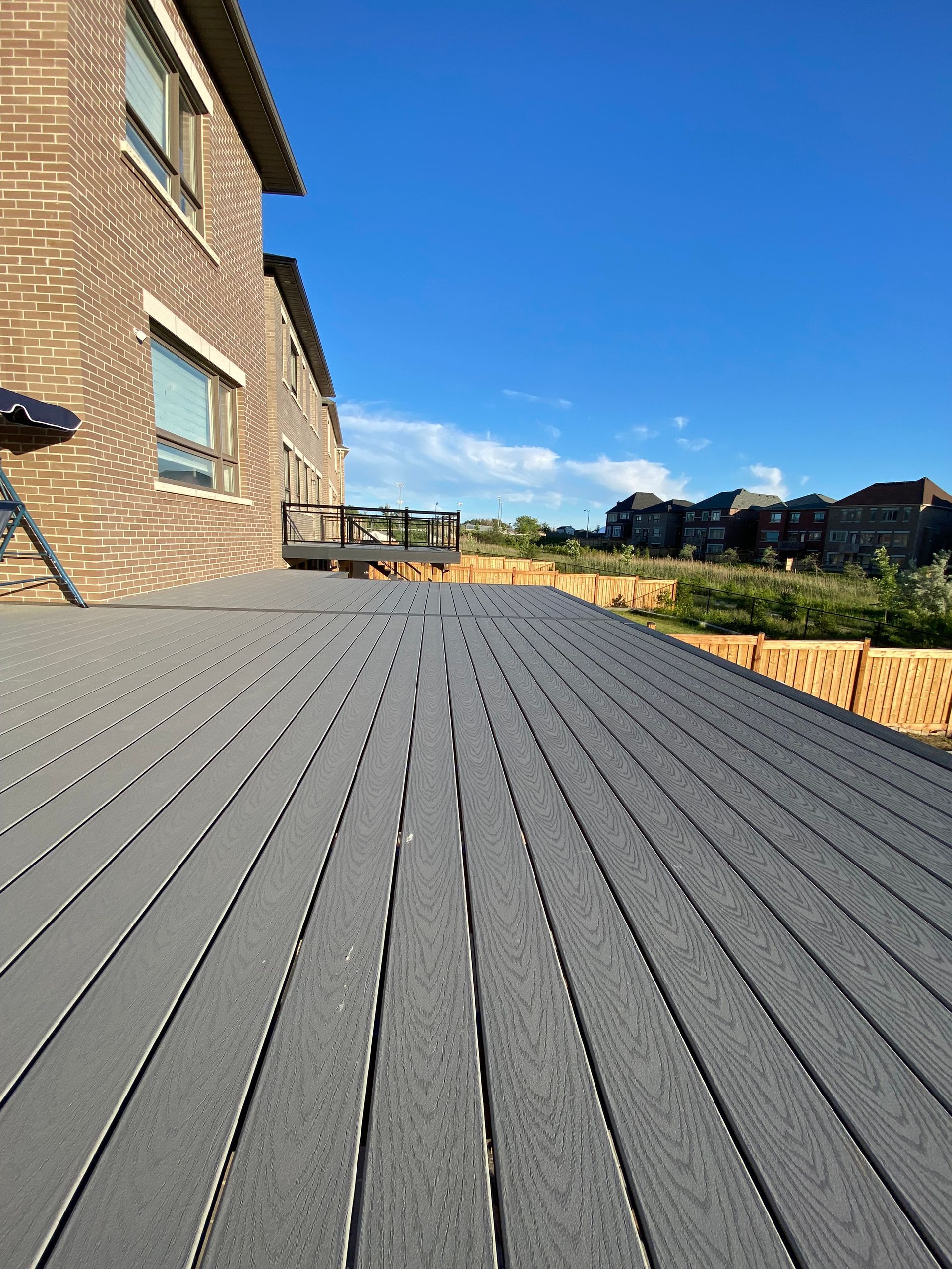 A gray deck with a brick building in the background.