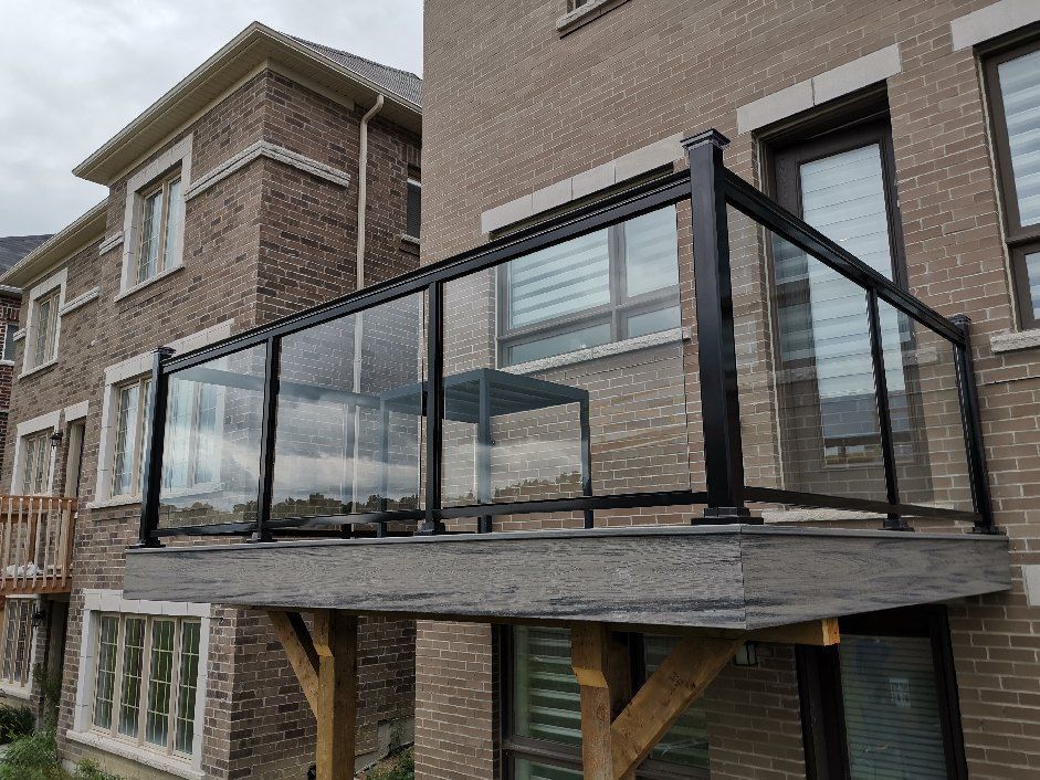 A balcony with a glass railing on the side of a brick building.