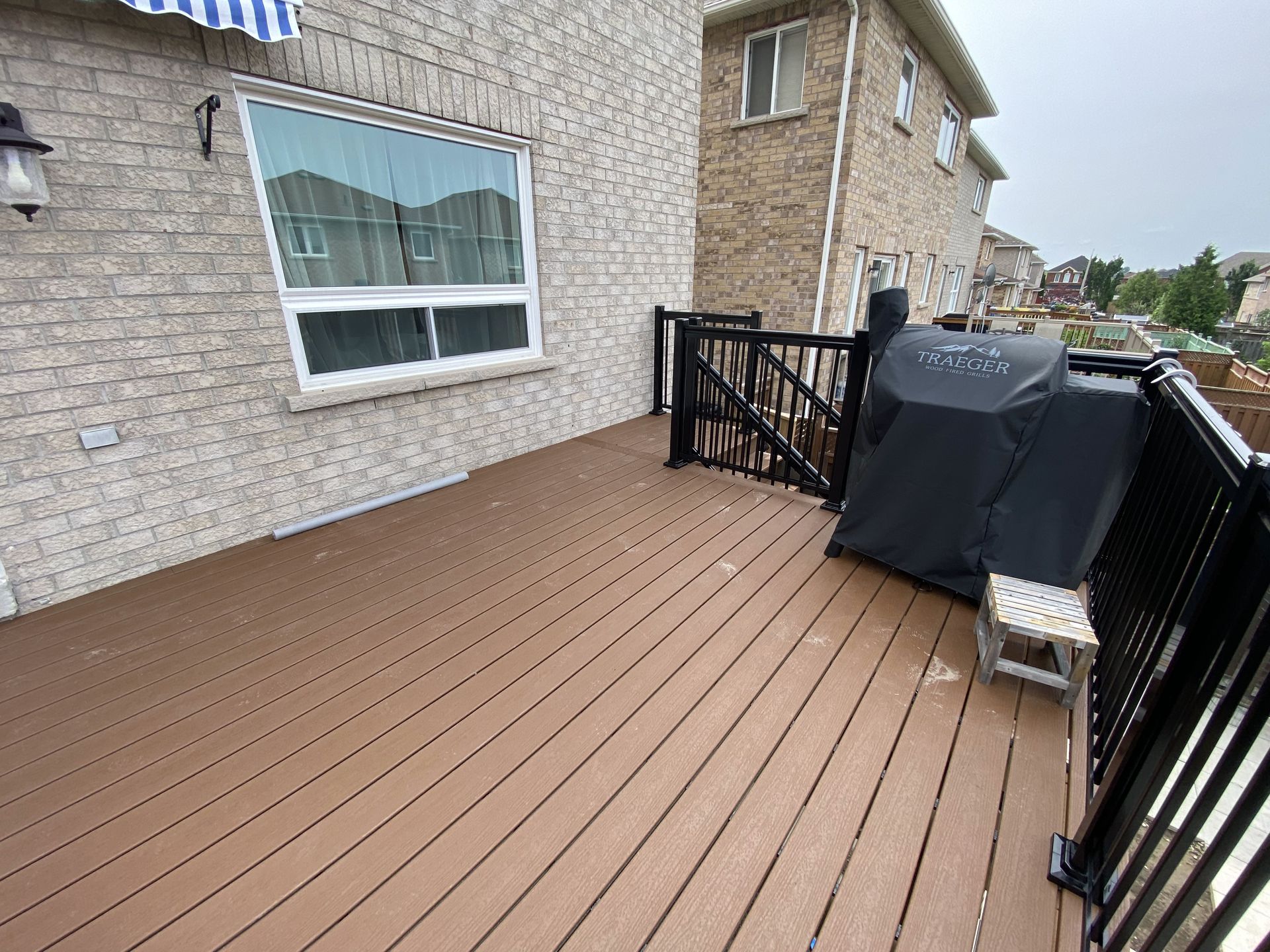 A wooden deck with a grill on it next to a house.