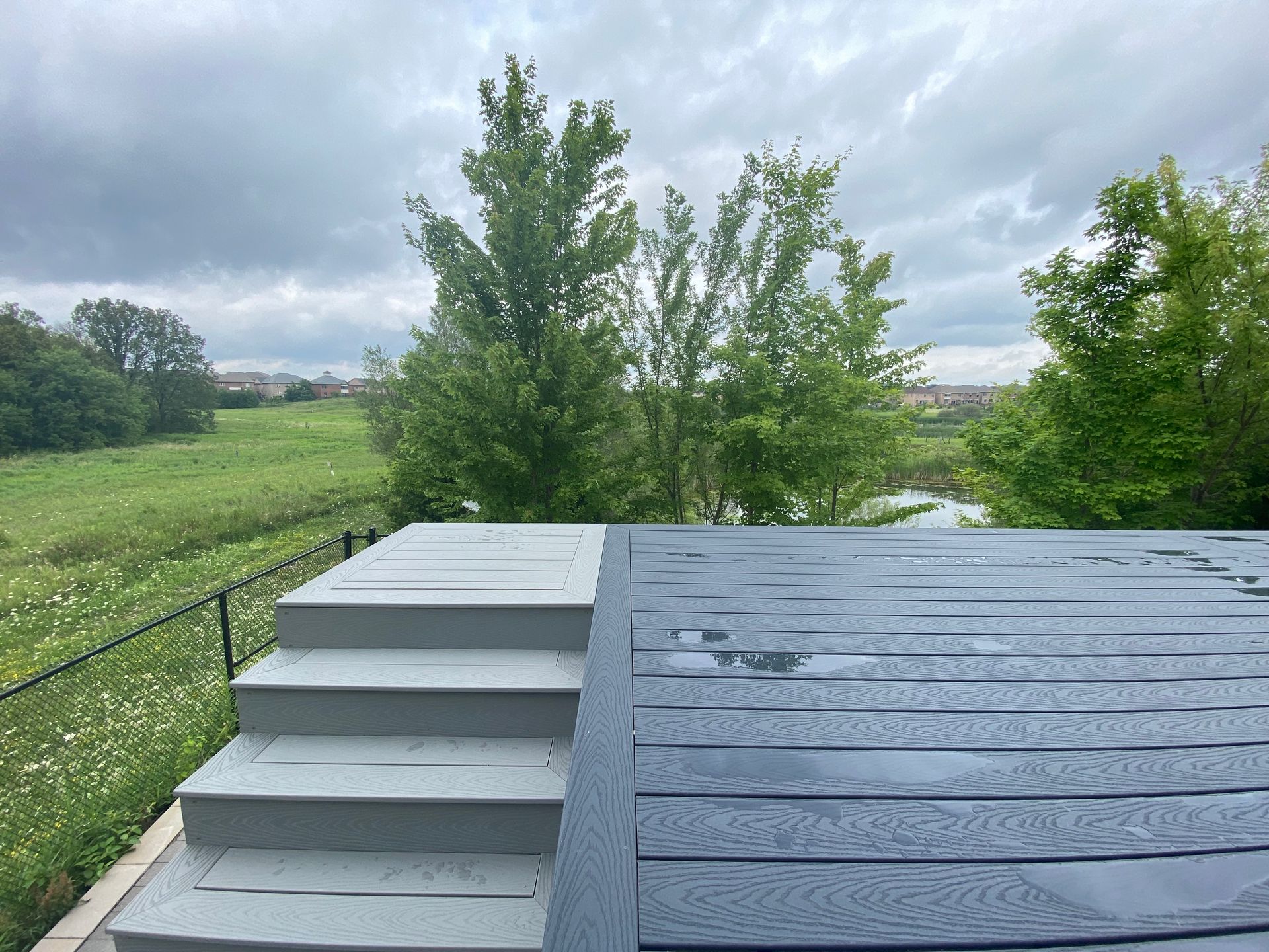 A wooden deck with stairs leading up to it and a view of a field.
