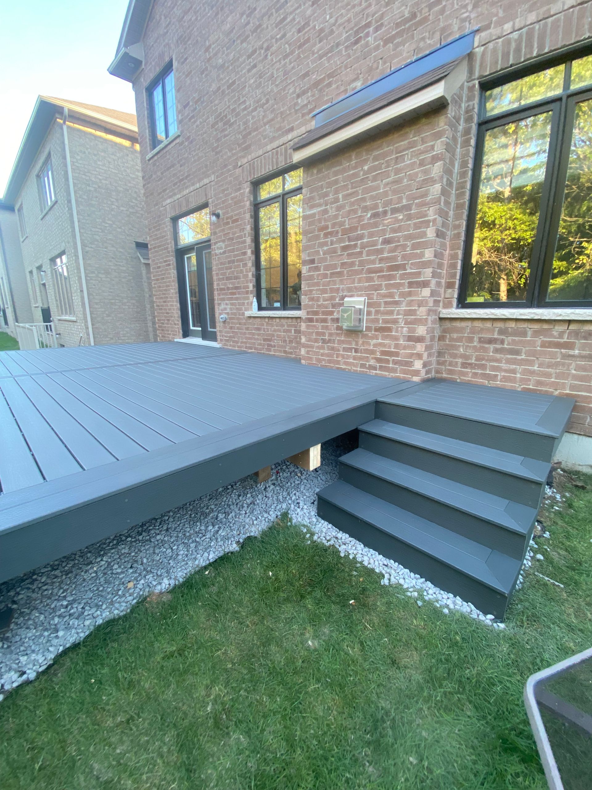 A brick house with a deck and stairs in front of it.