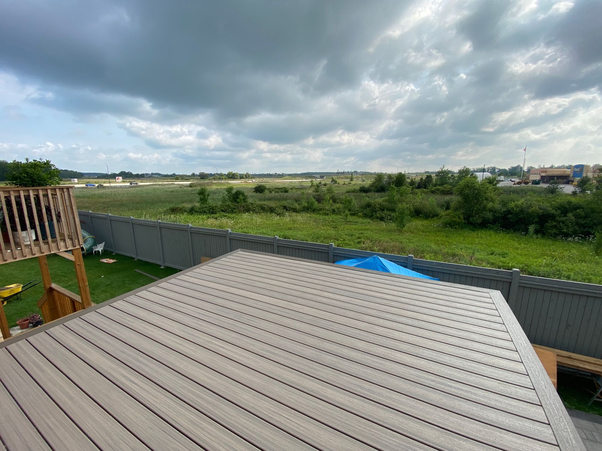 A deck with a view of a field and a fence.