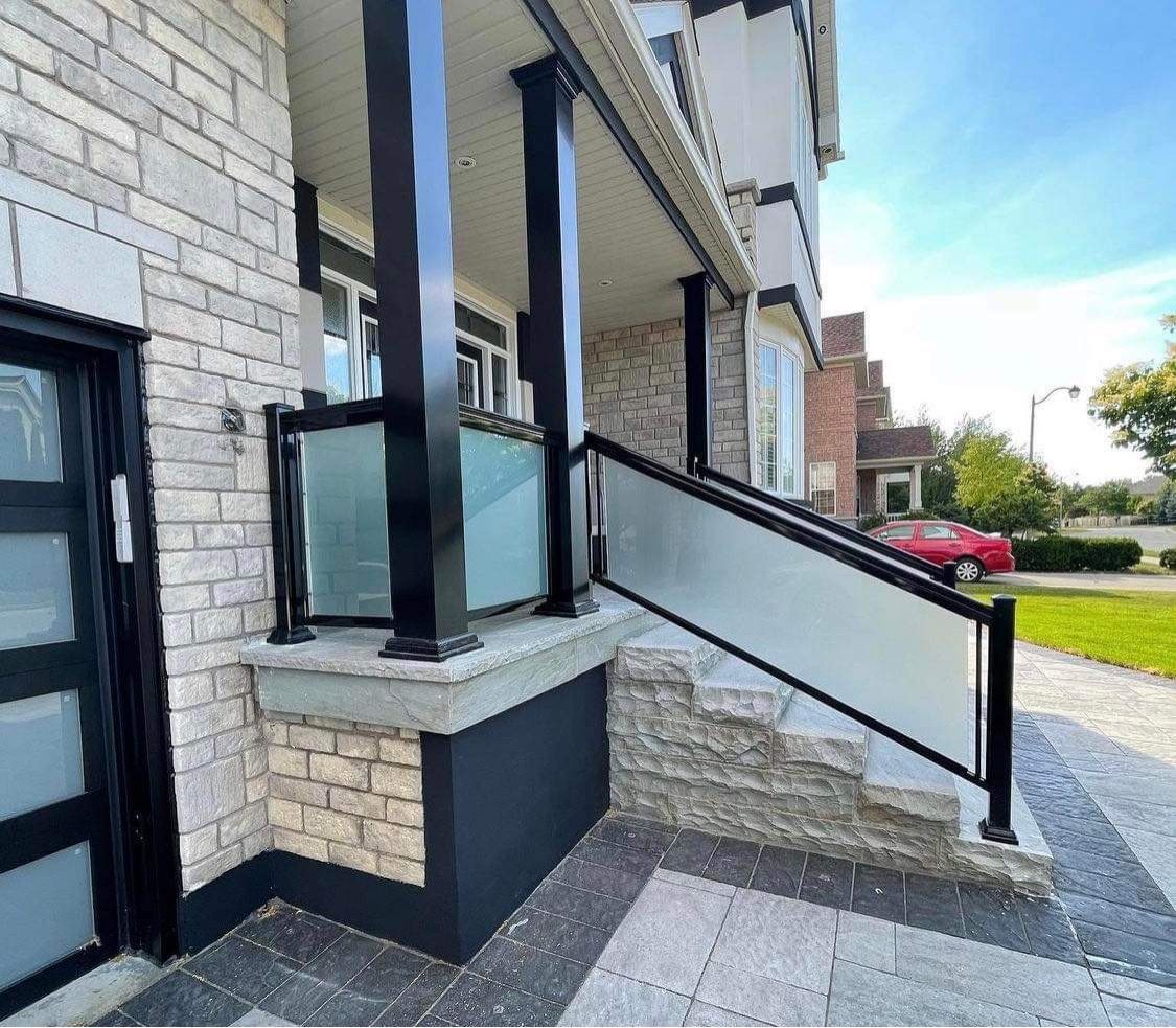 A brick house with a glass railing and stairs leading up to it.