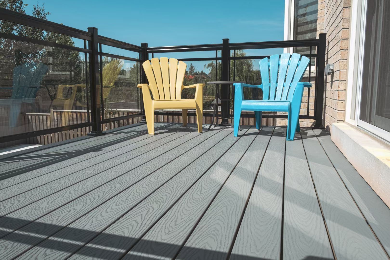 Two yellow and blue chairs are sitting on a gray deck.