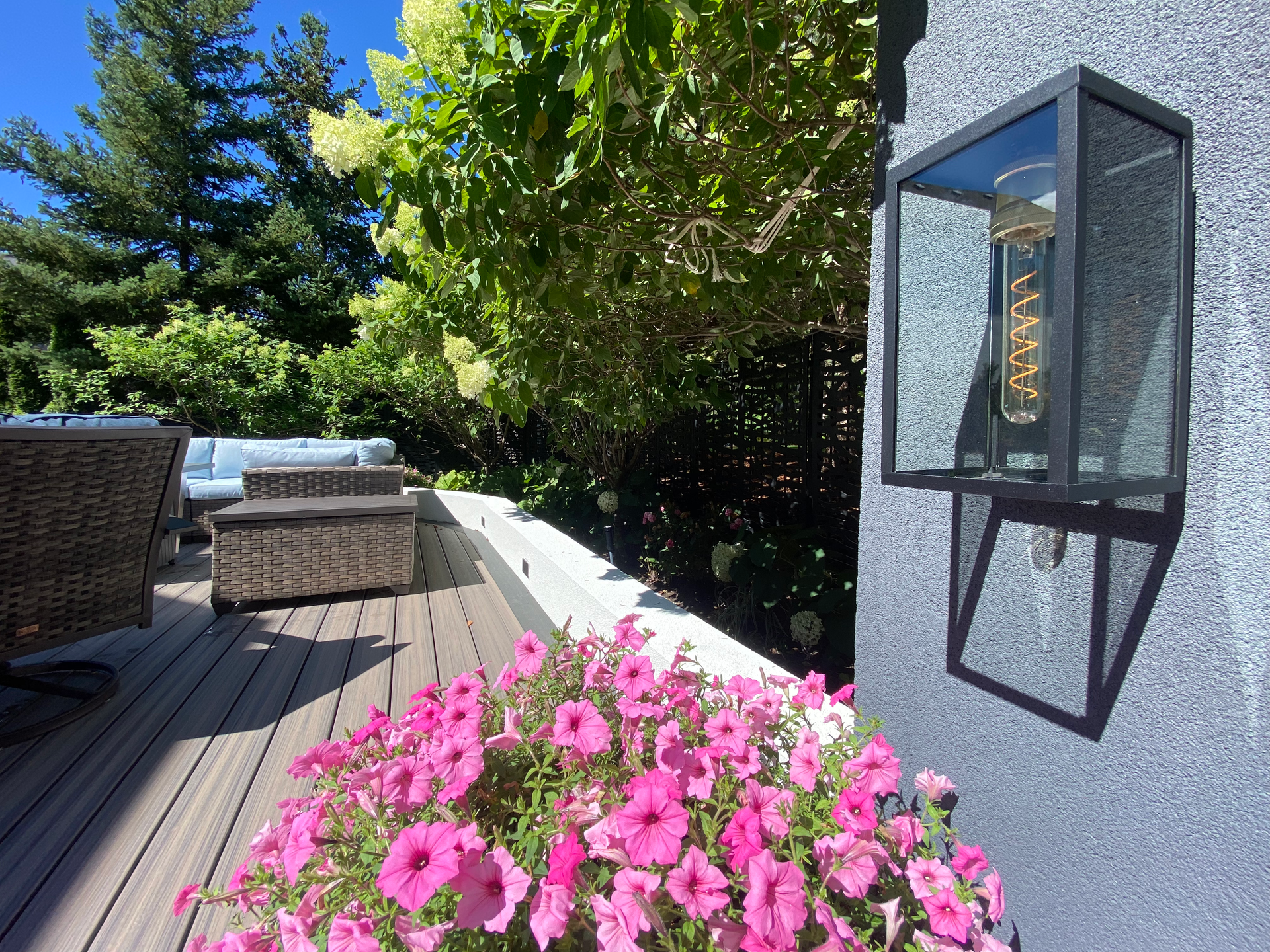 A deck with pink flowers and a light on the wall