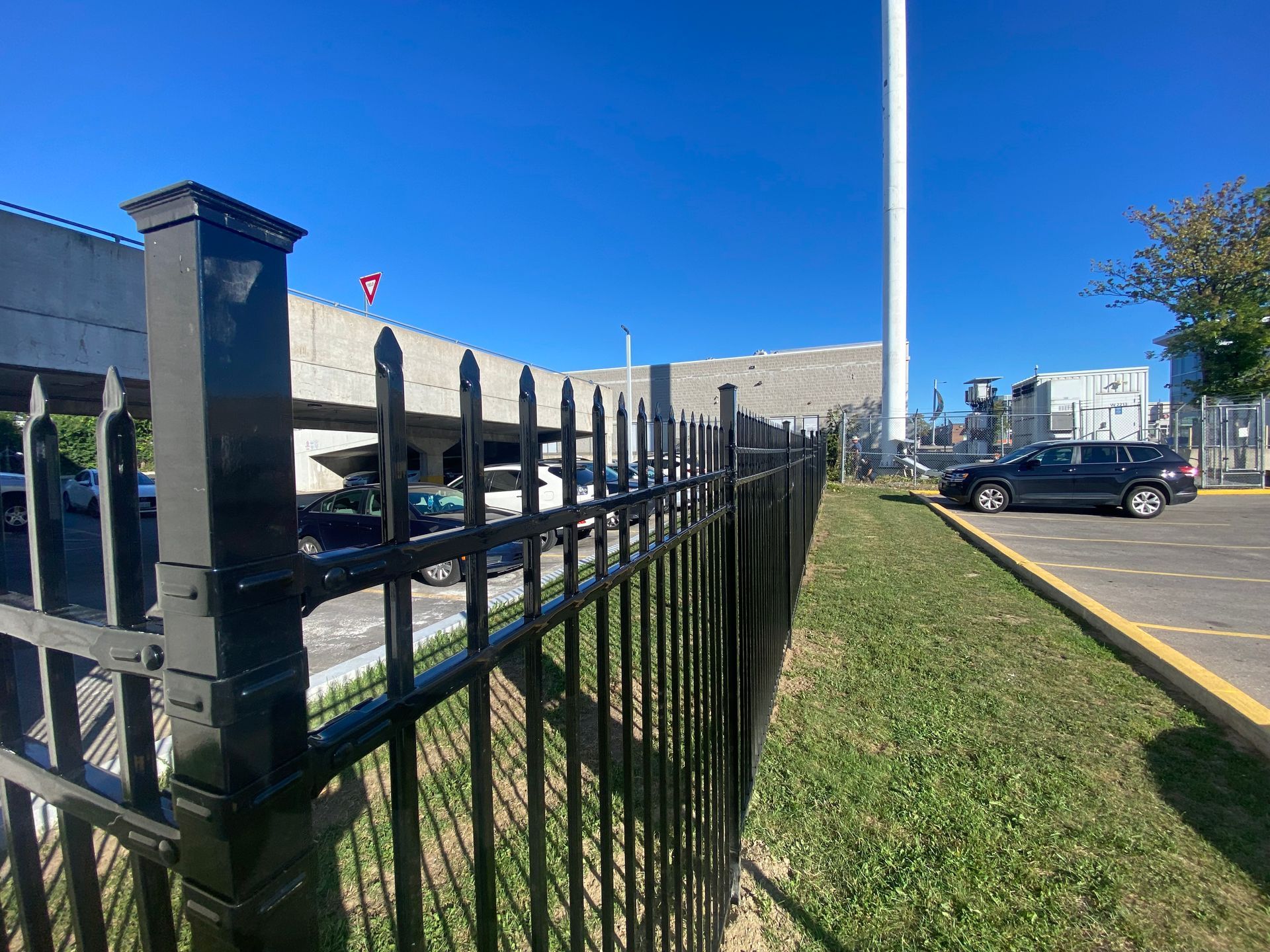 A black wrought iron fence surrounds a parking lot.