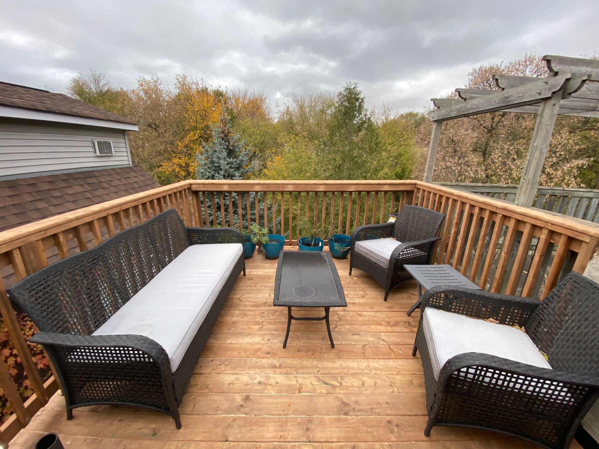 A wooden deck with a couch , chairs , table and potted plants.
