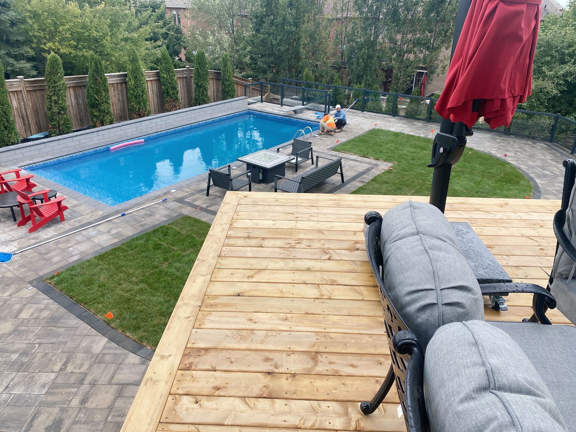 A view of a swimming pool from a wooden deck.
