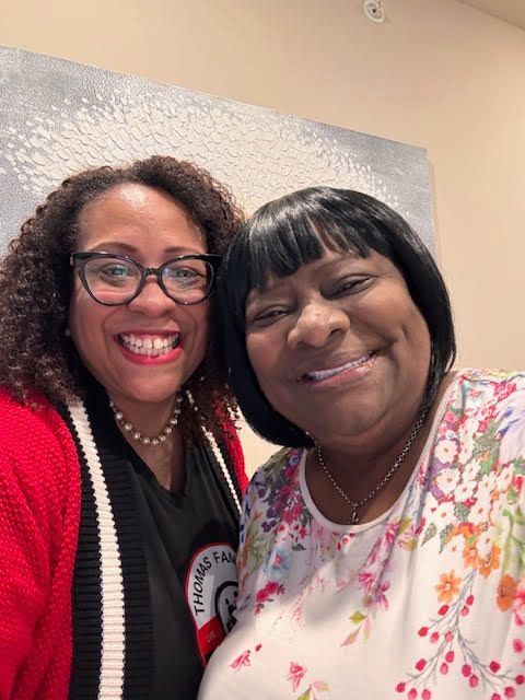 Two women are posing for a picture together and smiling for the camera.