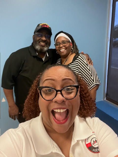 A man and two women are posing for a picture with a woman sticking her tongue out.