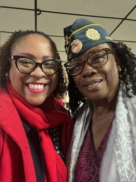 Two women are posing for a picture and one has a hat on