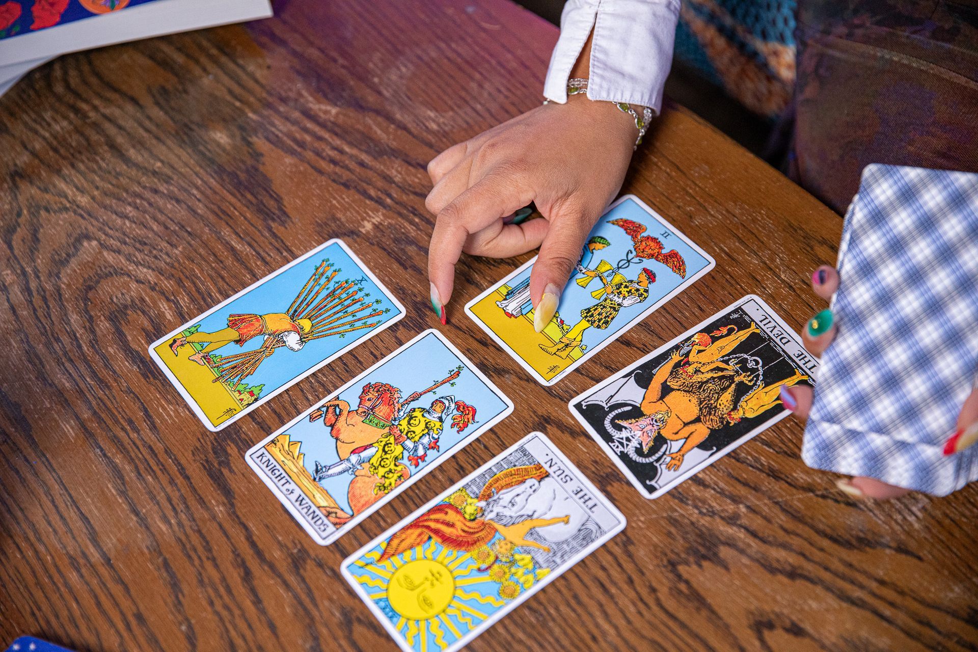 A person is playing tarot cards on a wooden table.