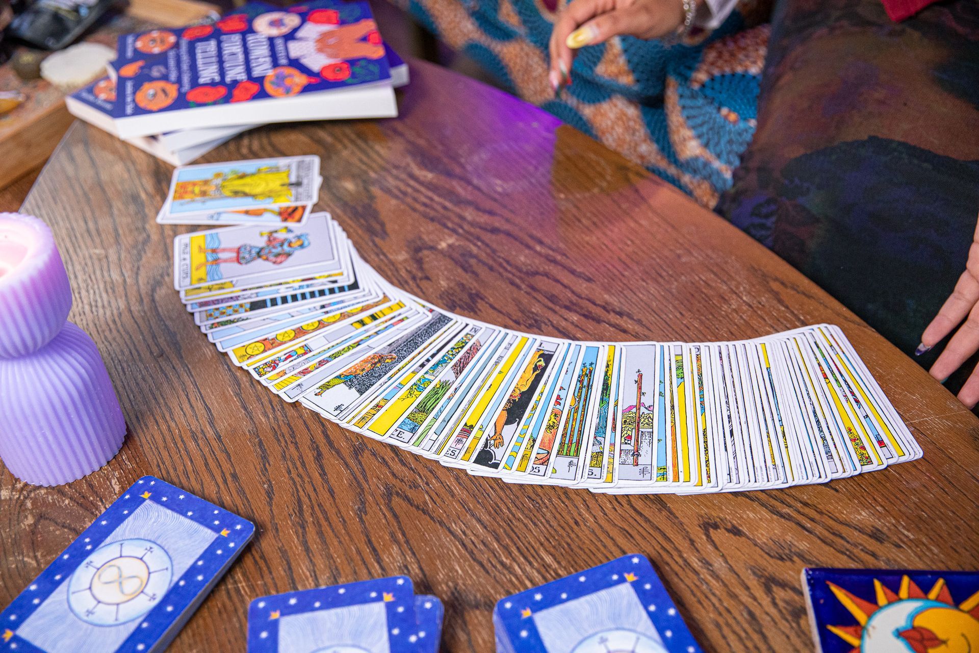 A person is playing tarot cards on a wooden table.
