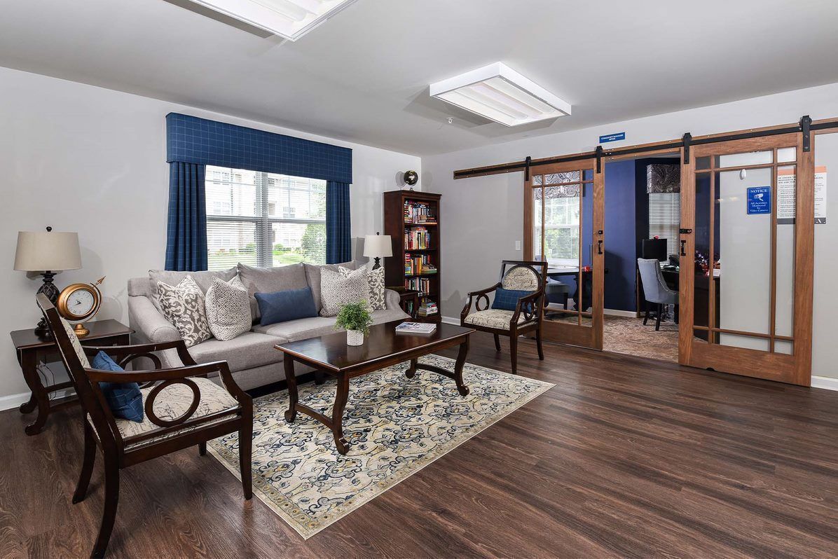 Lounge area with sofa, chairs, rug, bookshelf, and sliding barn doors to a work area.