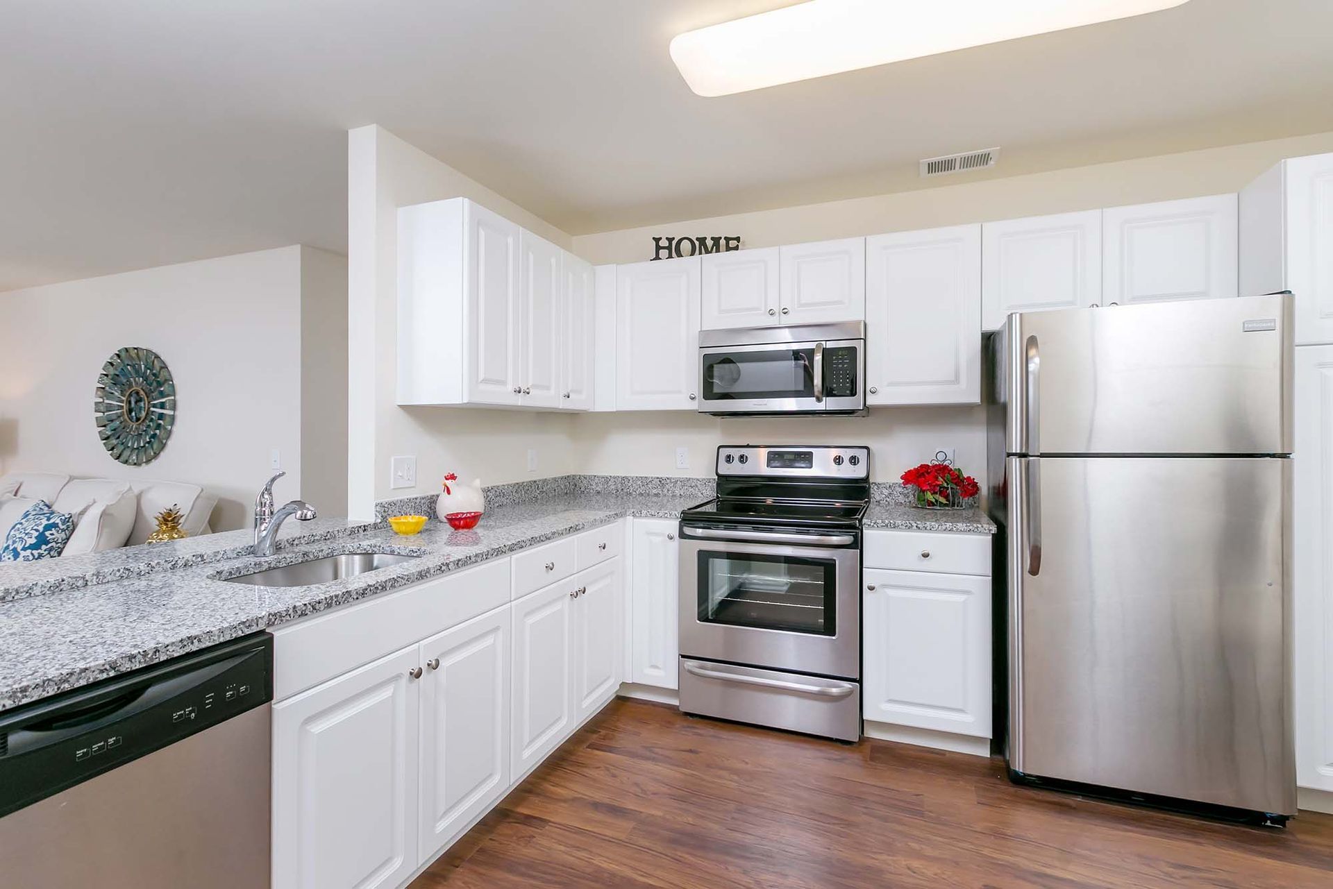 White kitchen with granite countertops and stainless steel appliances in an apartment