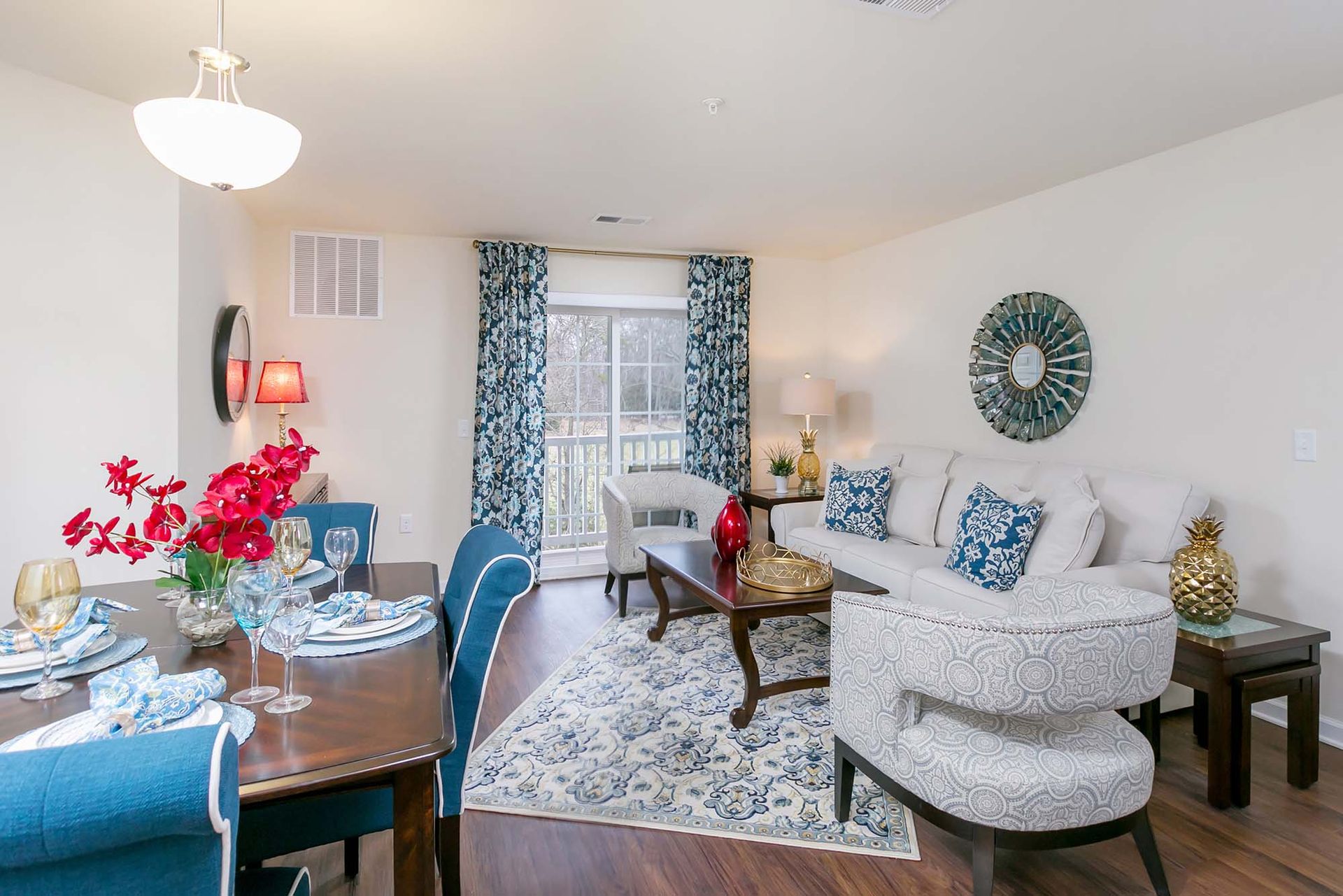 Living room and dining area in an apartment with a white sofa, blue accents, and sliding balcony door.