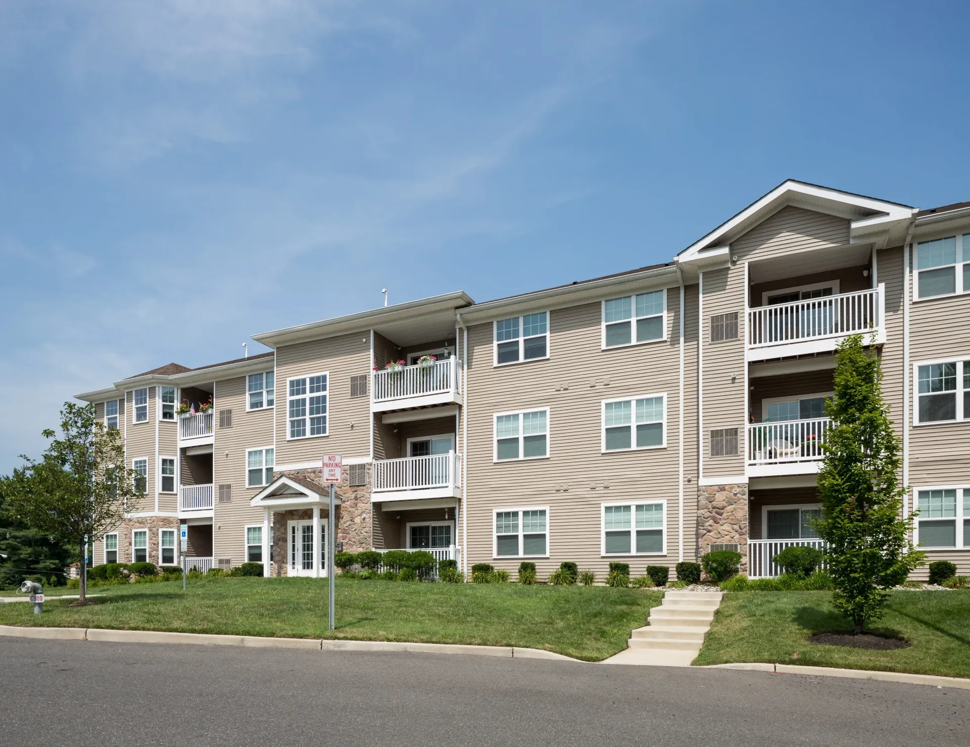 Exterior view of a beige multi-story apartment building with balconies and landscaping.