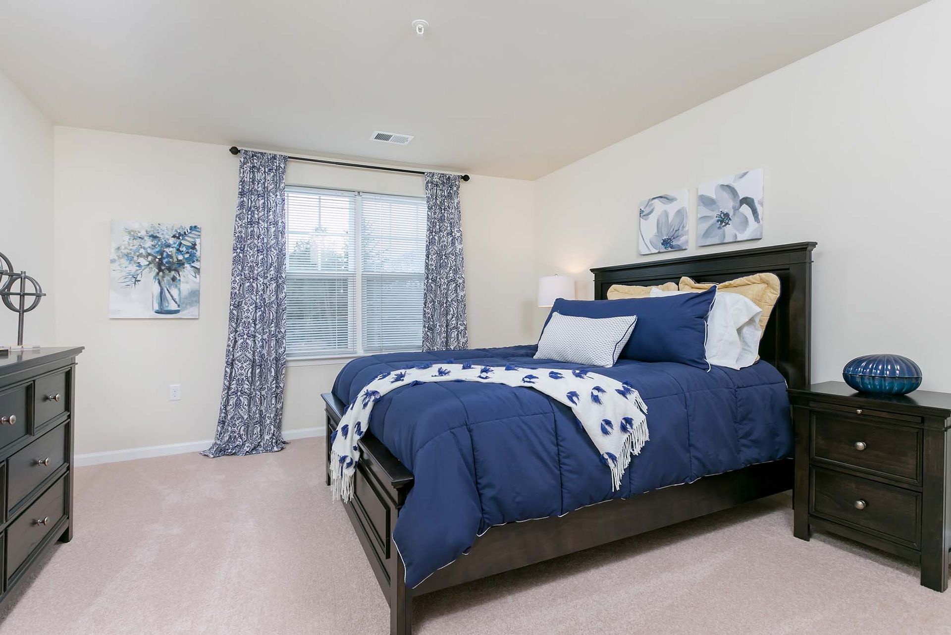 Bedroom with dark wood bed frame, navy bedding, and matching nightstands.