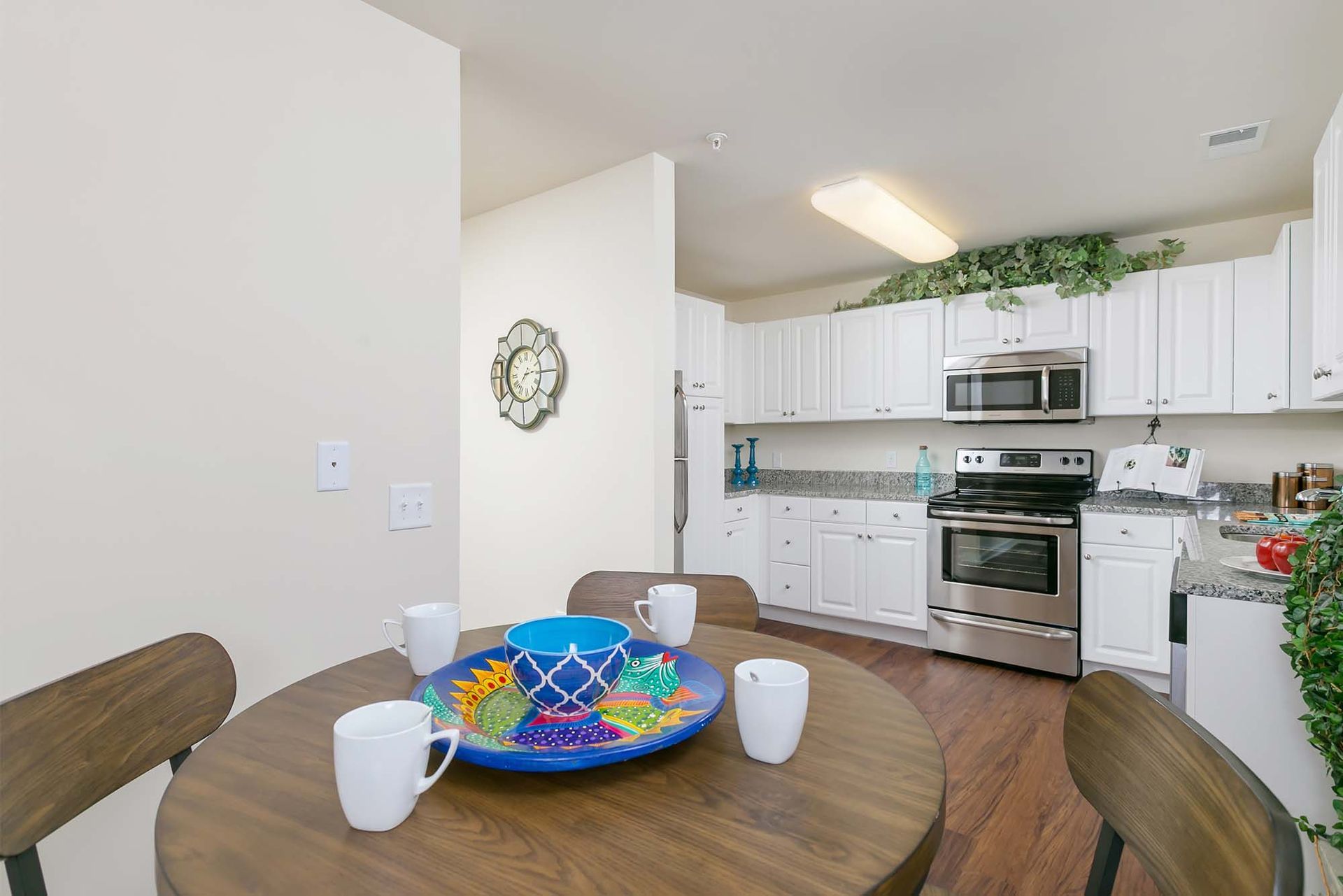 Kitchen with white cabinets, stainless steel appliances, and a round wooden dining table.
