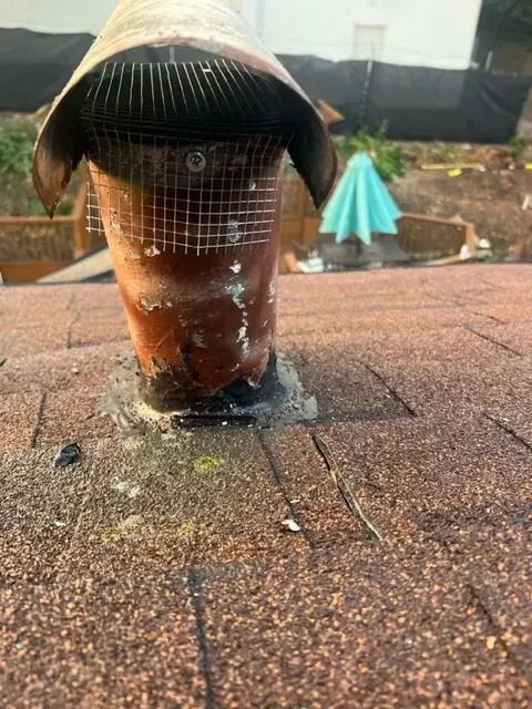 A chimney is sitting on top of a brick roof.