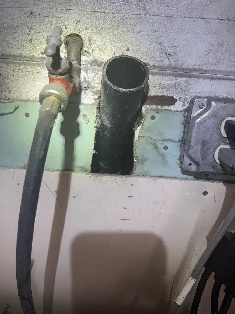 A close up of a hose connected to a pipe on a wall.