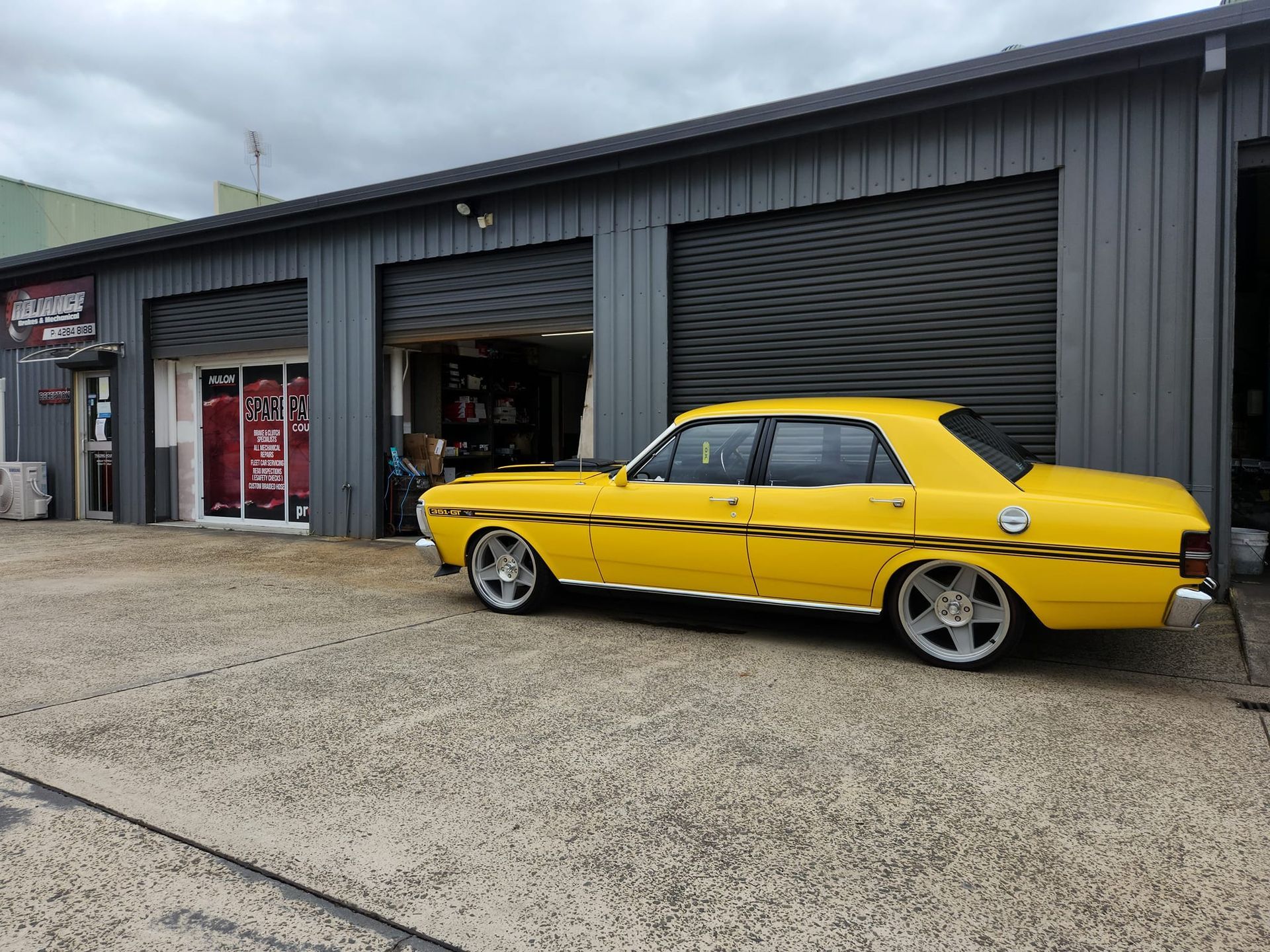 A yellow car is parked in front of a garage.