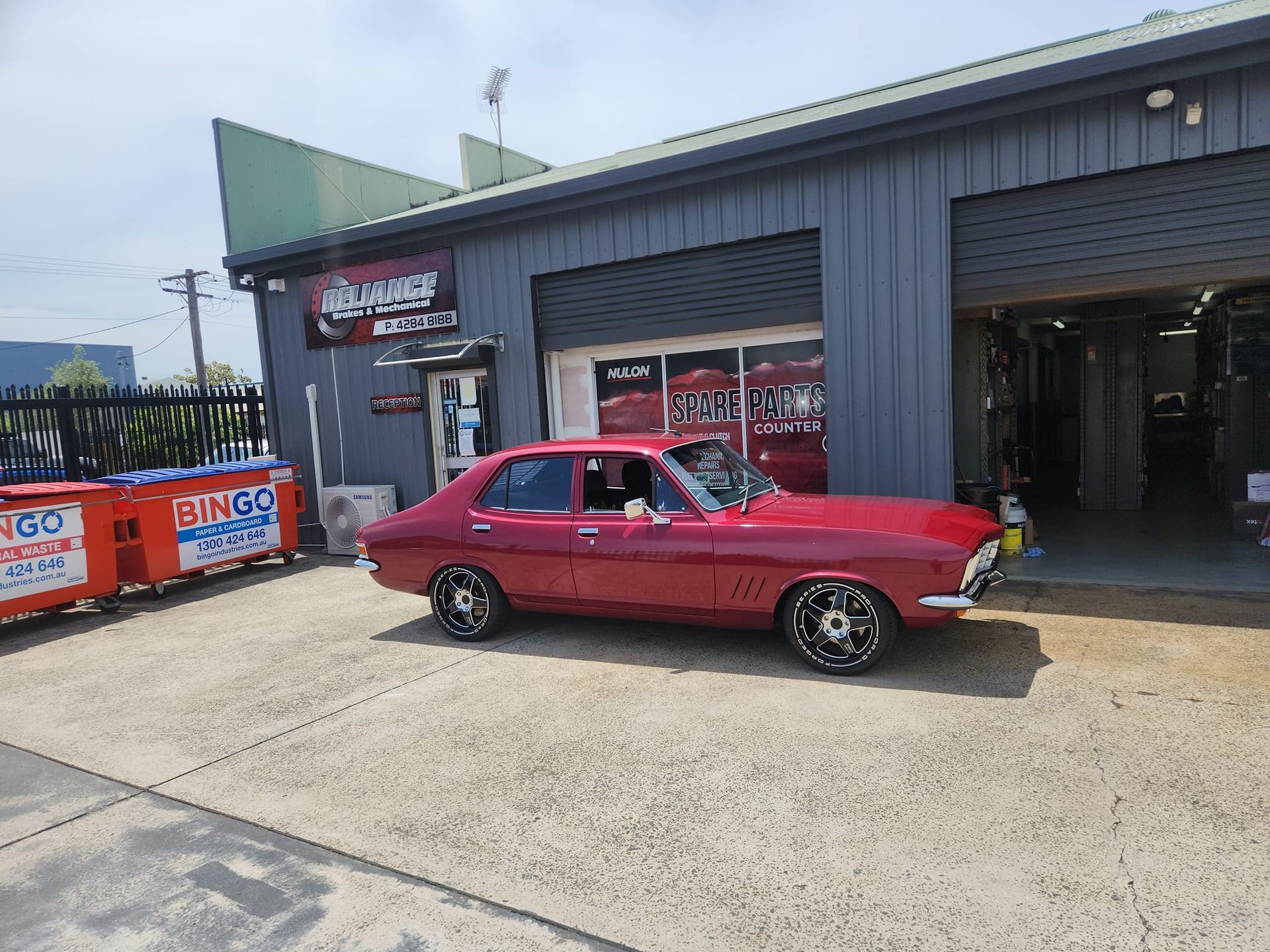 A red car is parked in front of a garage.