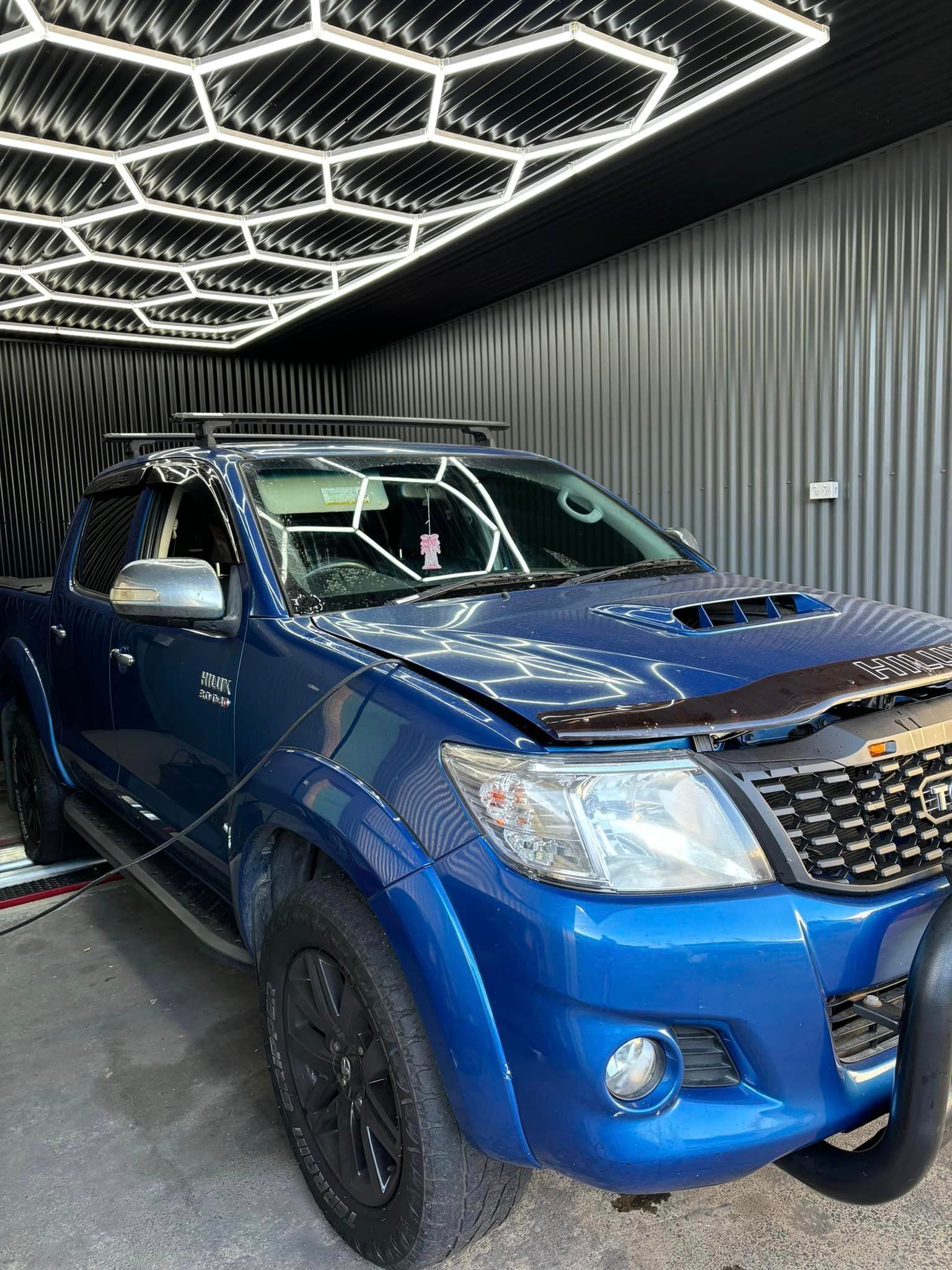 A blue toyota hilux is parked in a garage.