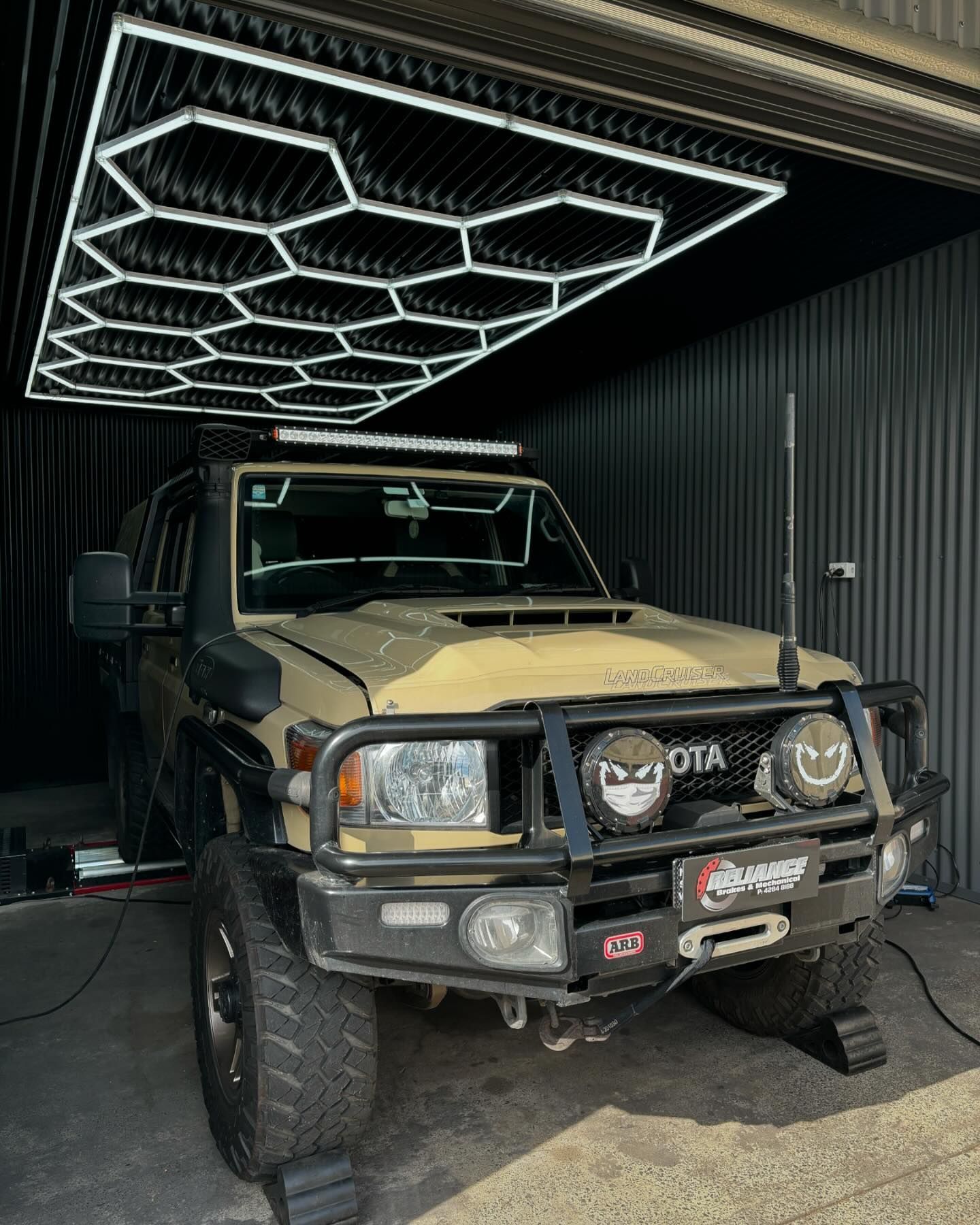 A toyota land cruiser is parked in a garage under a ceiling light.