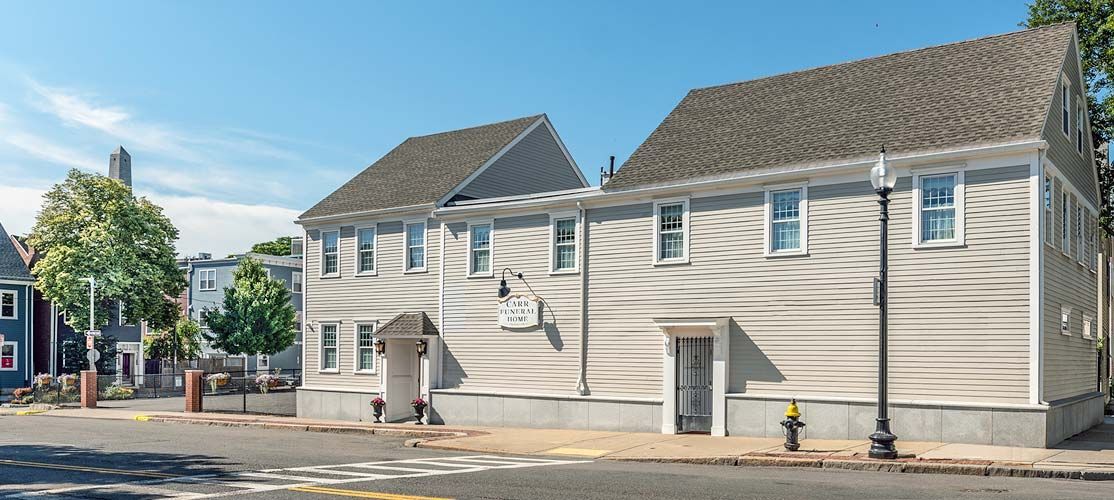 Tall ship docked against a blue sky, cityscape in the background.