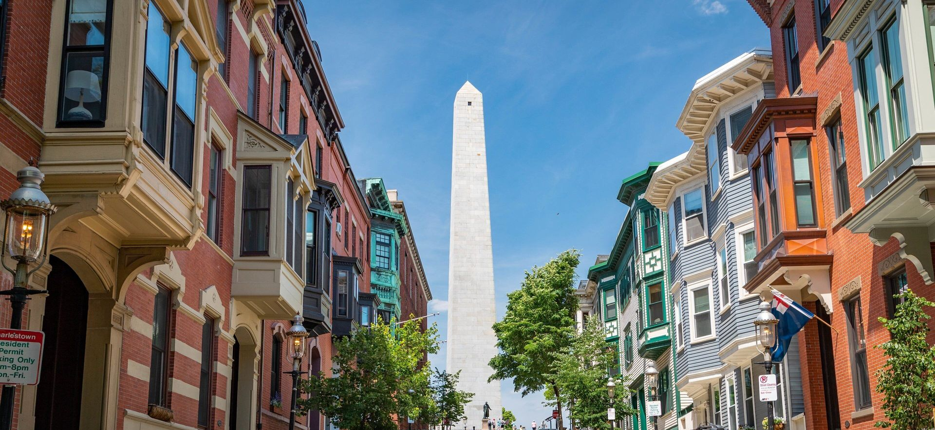 Tall ship docked against a blue sky, cityscape in the background.