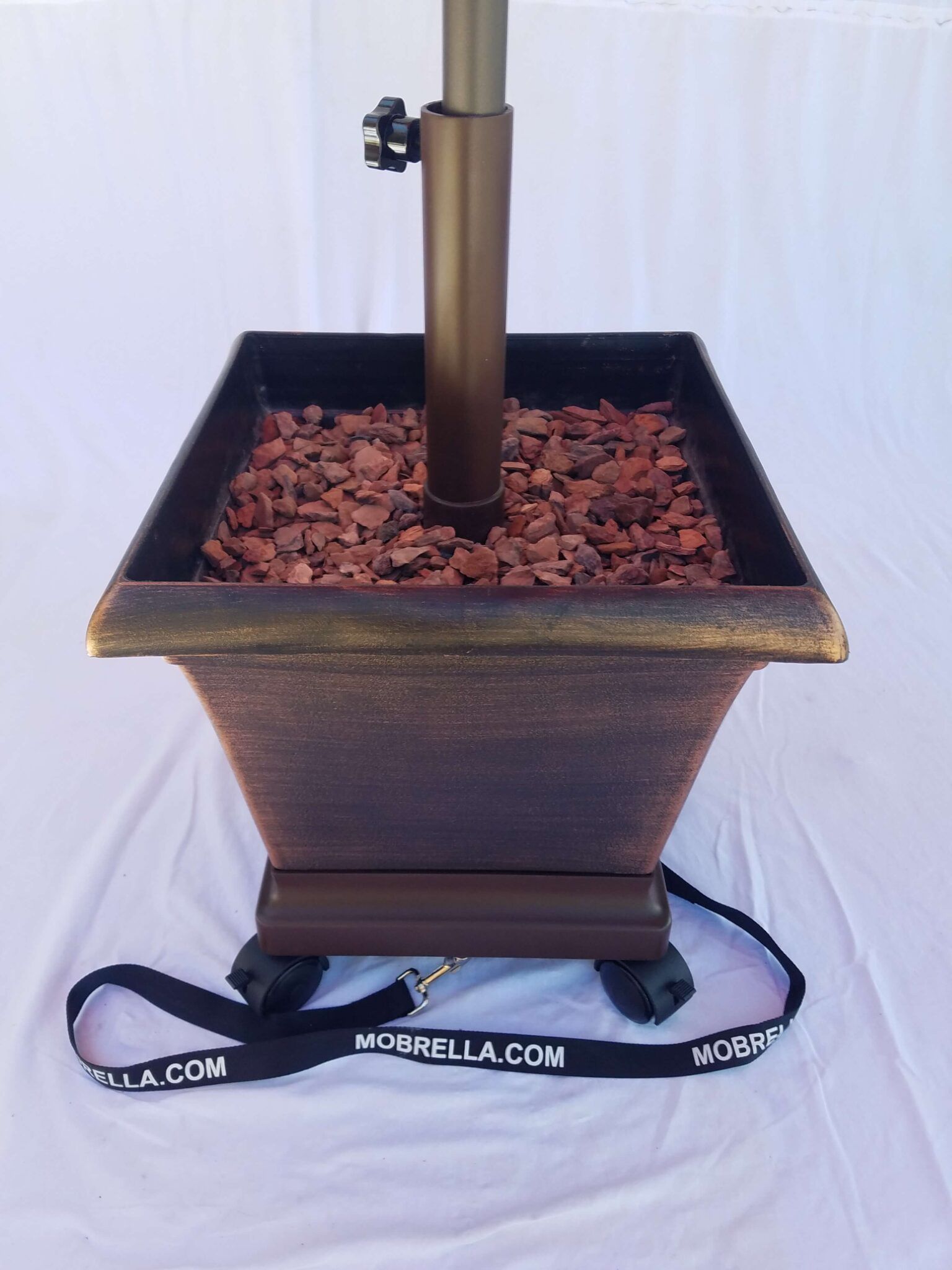 An umbrella is sitting in a planter filled with rocks.